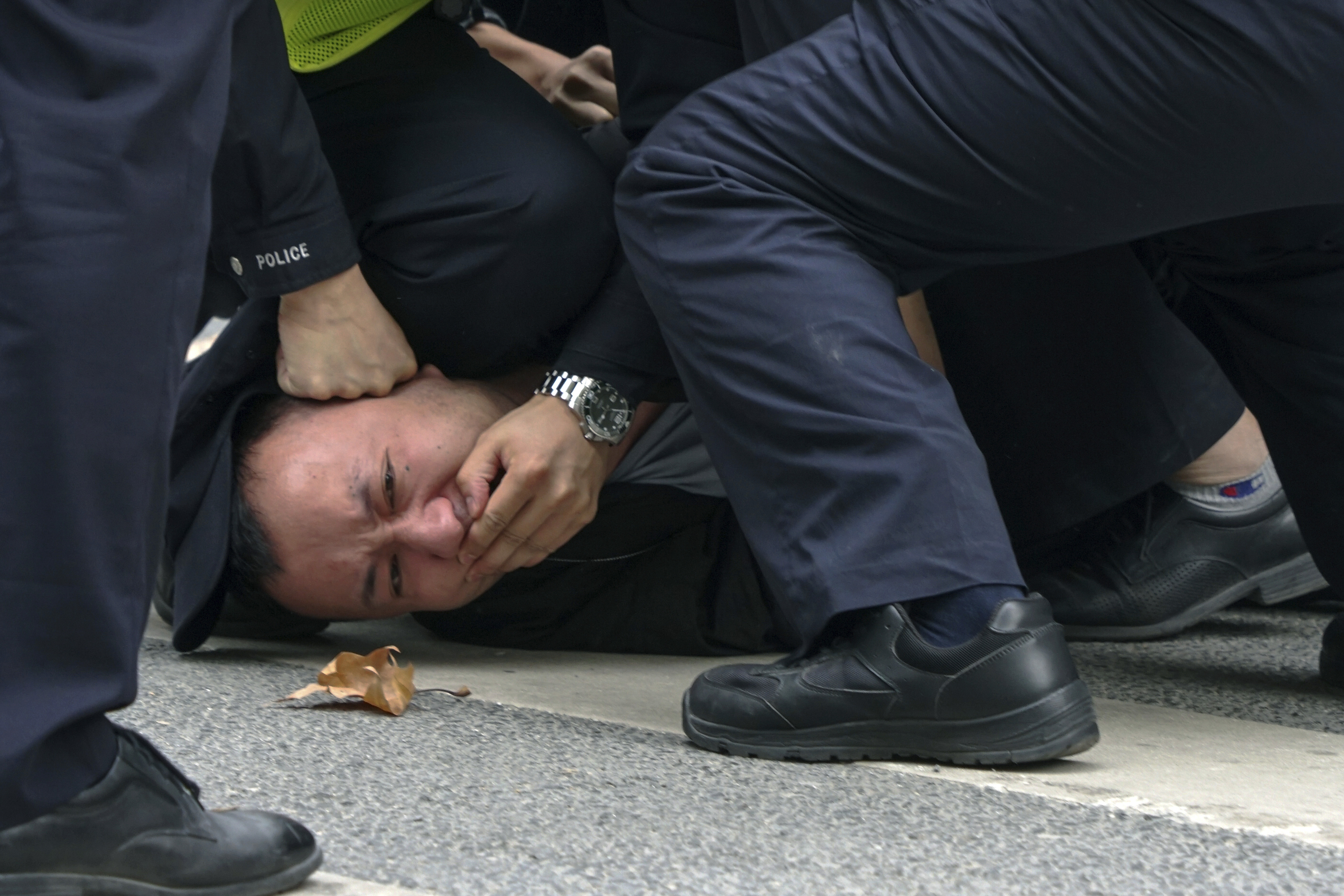 In this photo taken on Sunday, policemen pin down and arrest a protester during a protest on a street in Shanghai, China.