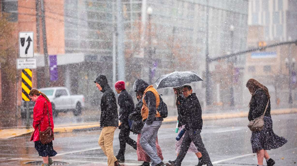 People walk across 300 West in downtown Salt City Lake as snow falls Monday afternoon. The city and other Wasatch Front valley areas are included in a winter weather advisory Monday and Tuesday.