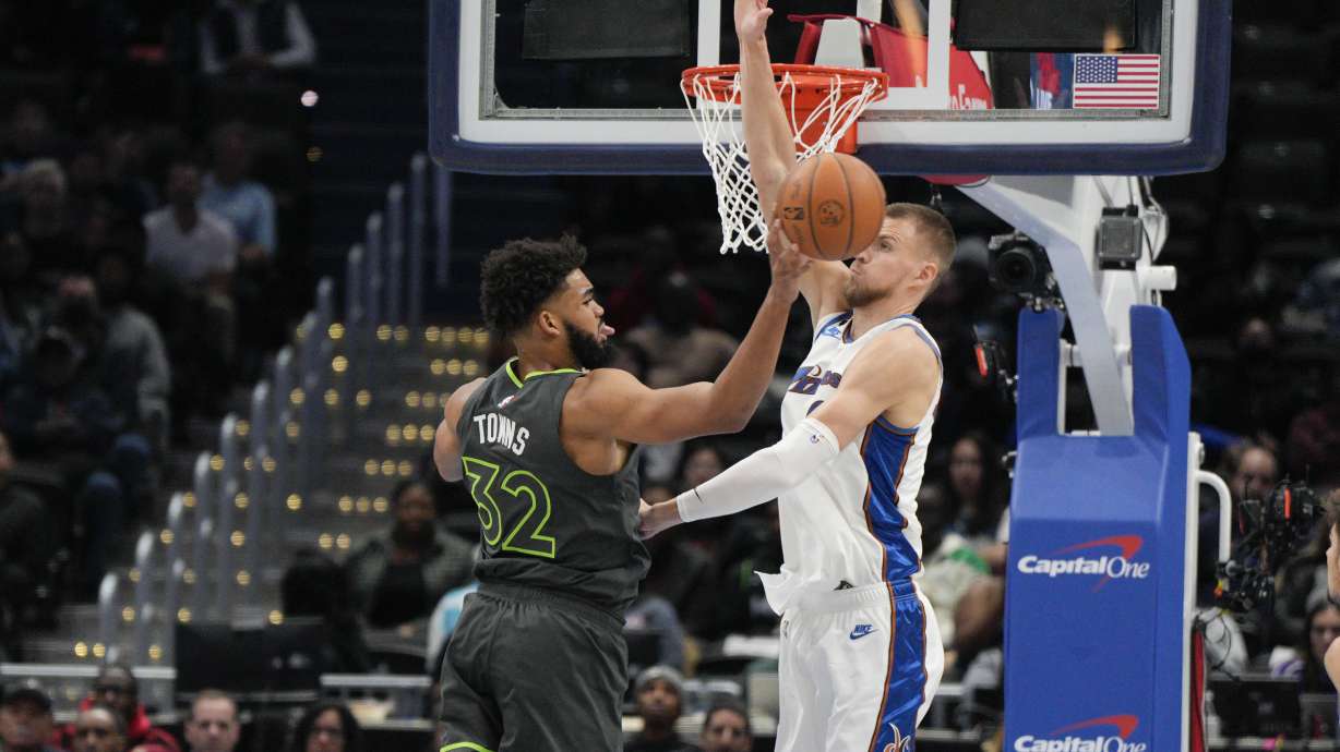 Minnesota Timberwolves center Karl-Anthony Towns (32) passes in front of Washington Wizards center Kristaps Porzingis, right, during the first half of an NBA basketball game, Monday, Nov. 28, 2022, in Washington.