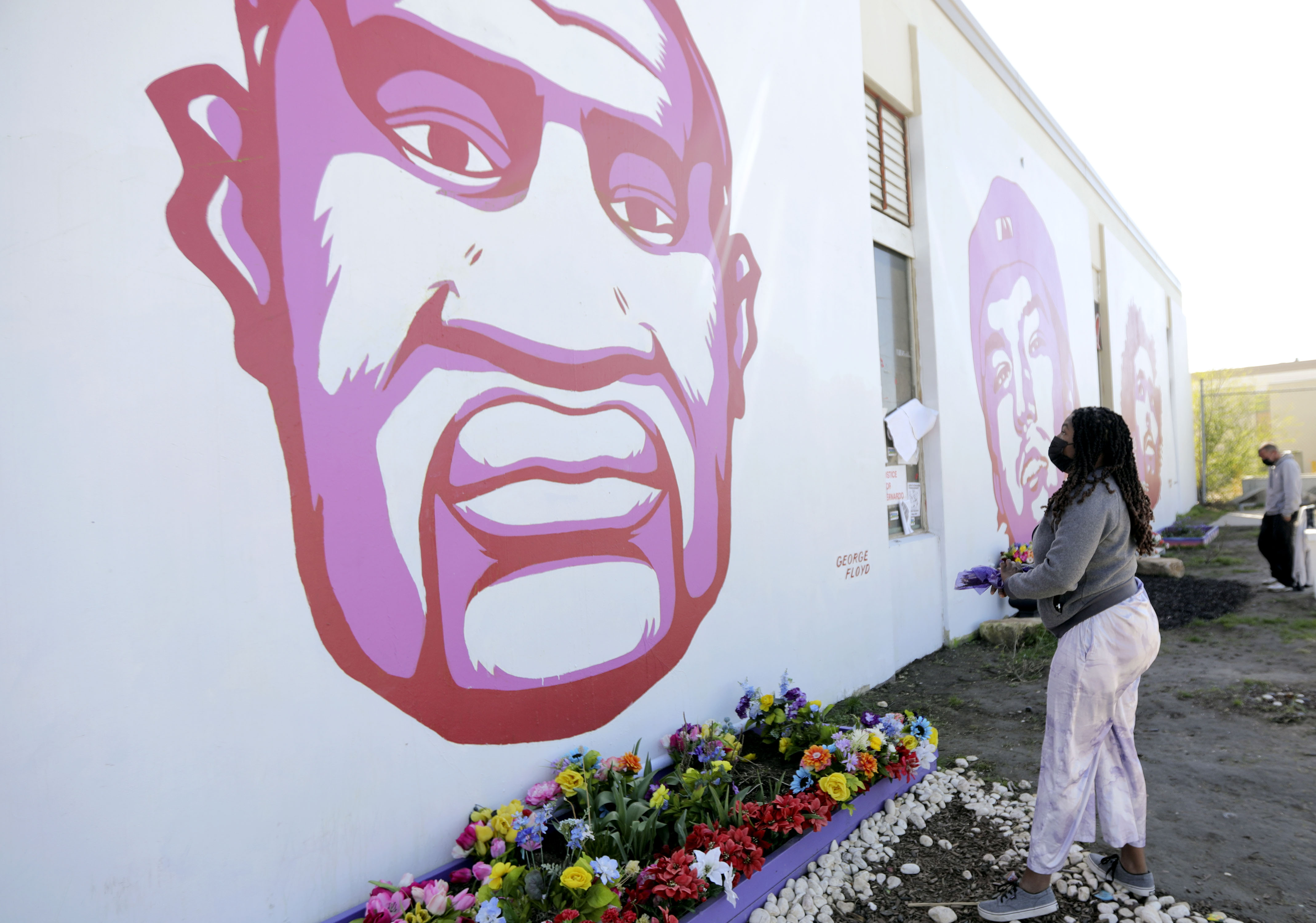 Ashley Cleveland brings flowers to the George Floyd mural in Salt Lake City on April 20, 2021. The buildings where the Floyd mural and 28 more were painted are to be torn down, and a vigil is set for Saturday ahead of demolition.