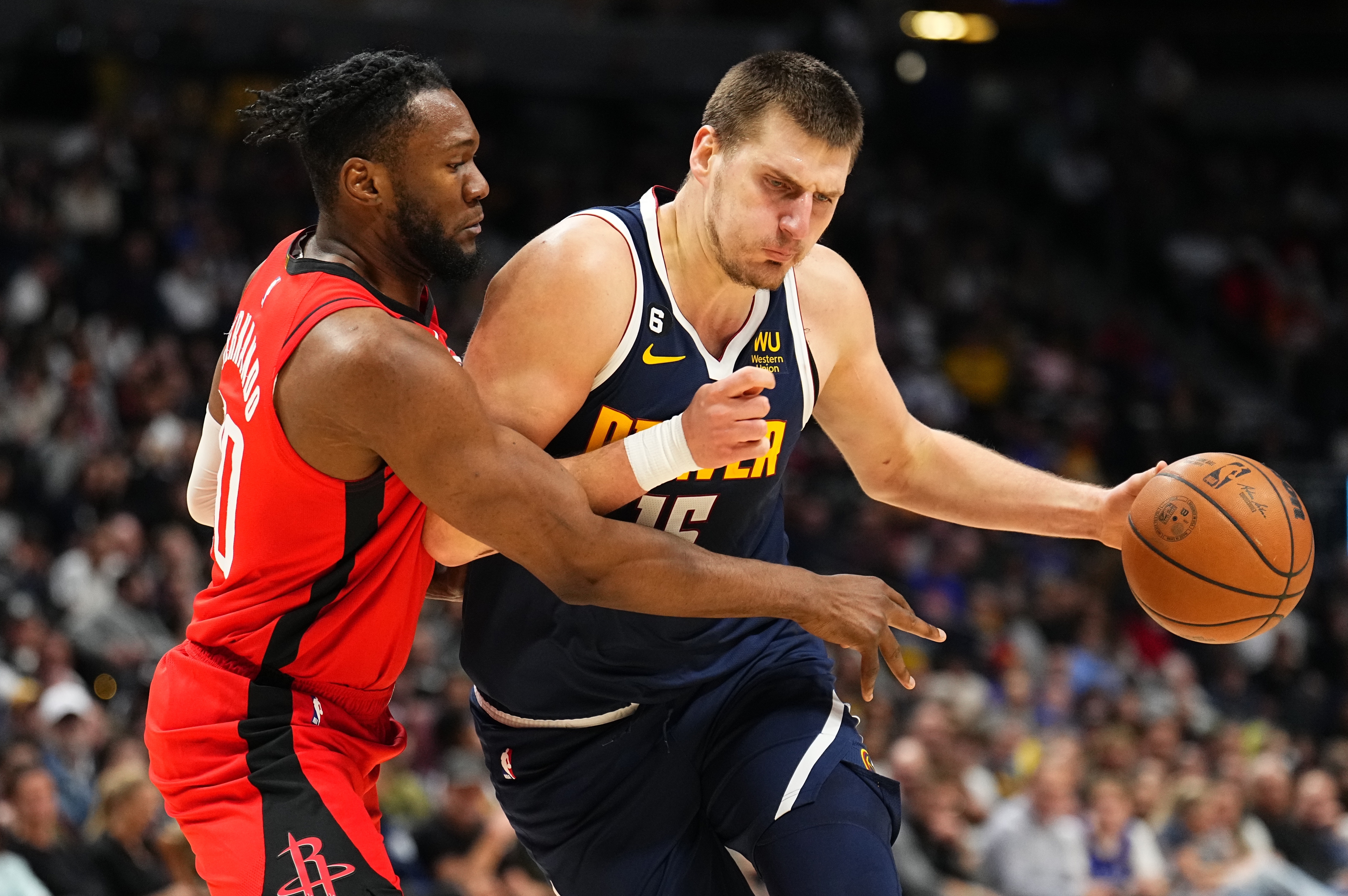 Denver Nuggets center Nikola Jokic, right, drives to the basket against Houston Rockets forward Bruno Fernando, left, during the third quarter of an NBA basketball game, Monday, Nov. 28, 2022, in Denver. 