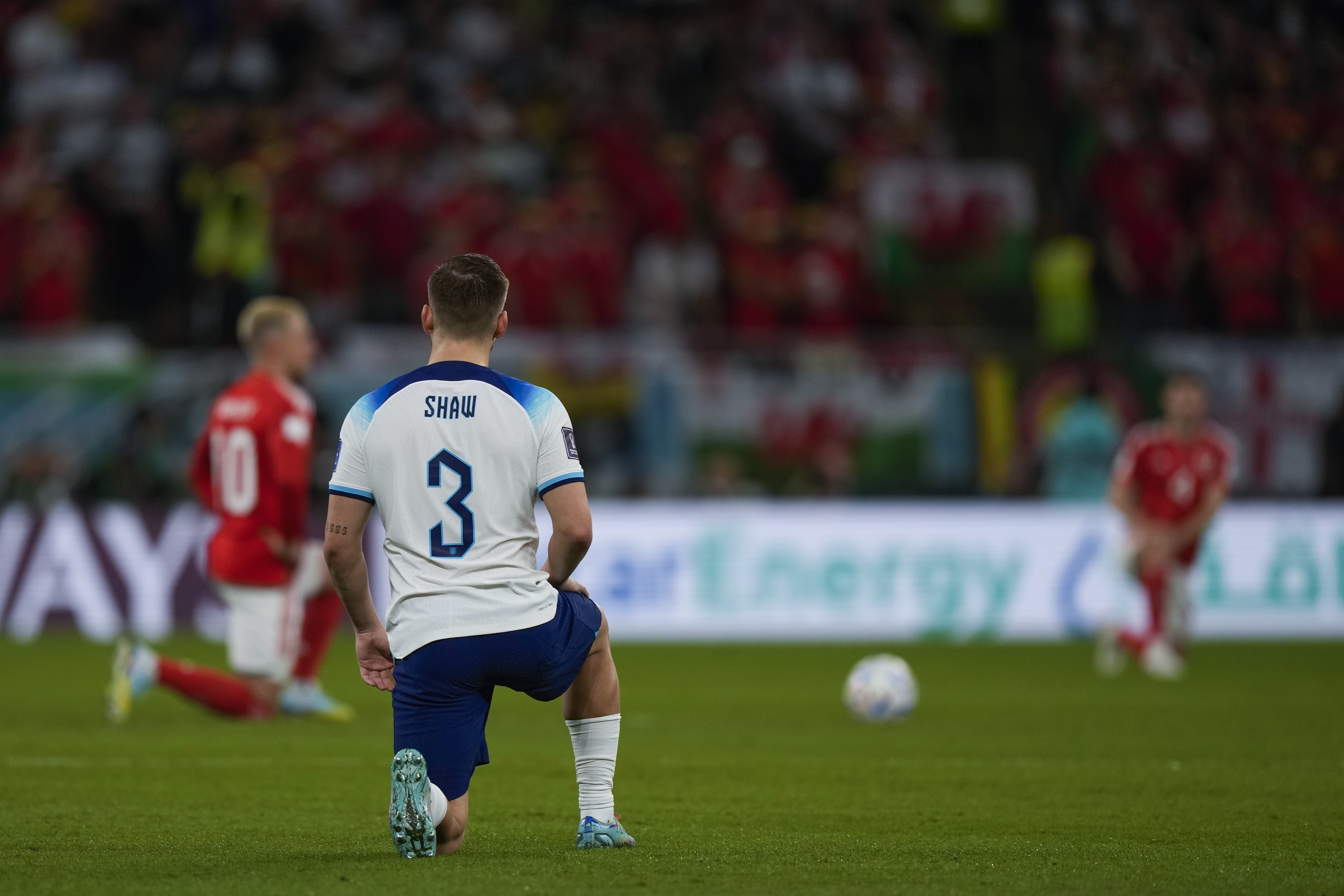 England's Luke Shaw knees along Wales players, background, just before the kick off of the World Cup group B soccer match between England and Wales, at the Ahmad Bin Ali Stadium in Al Rayyan , Qatar, Tuesday, Nov. 29, 2022.