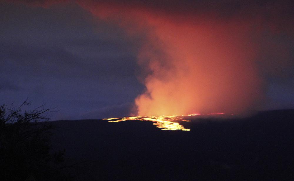 Lava pours out of the summit crater of Mauna Loa on Monday, as seen from Gilbert Kahele Recreation Area on Maunakea, Hawaii. Mauna Loa, the world’s largest active volcano, began spewing ash and debris from its summit, prompting civil defense officials to warn residents on Monday to prepare in case the eruption causes lava to flow toward communities.