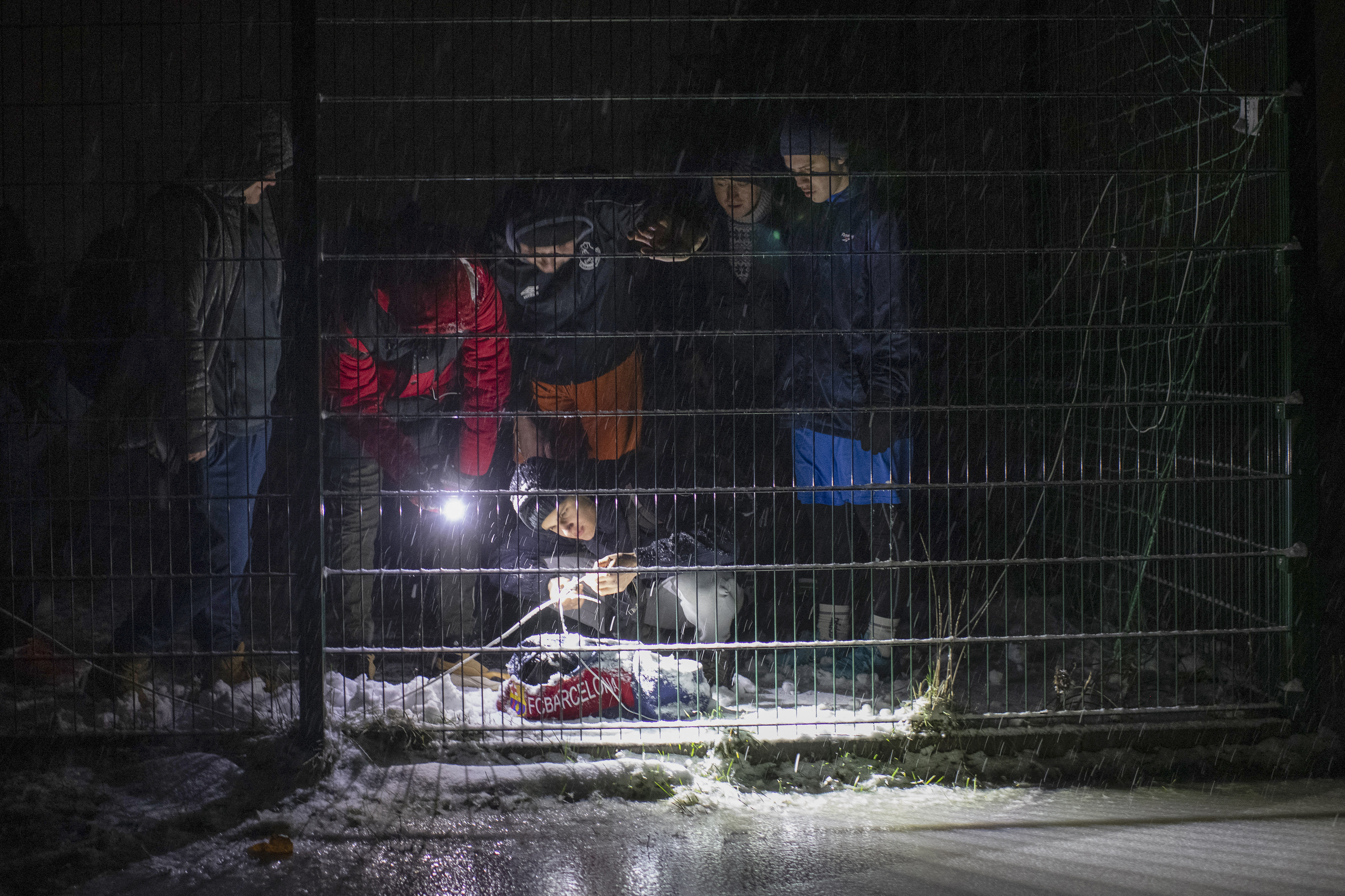 Men connect a homemade light with a battery to illuminate the pitch ahead of a soccer game during a blackout in Irpin, Kyiv region, Ukraine, Tuesday, Nov. 29, 2022. For soccer lovers in Ukraine, Russia's invasion and the devastation it has wrought have created uncertainties about both playing the sport and watching it. For Ukrainians these days, soccer trails well behind mere survival in the order of priorities. 