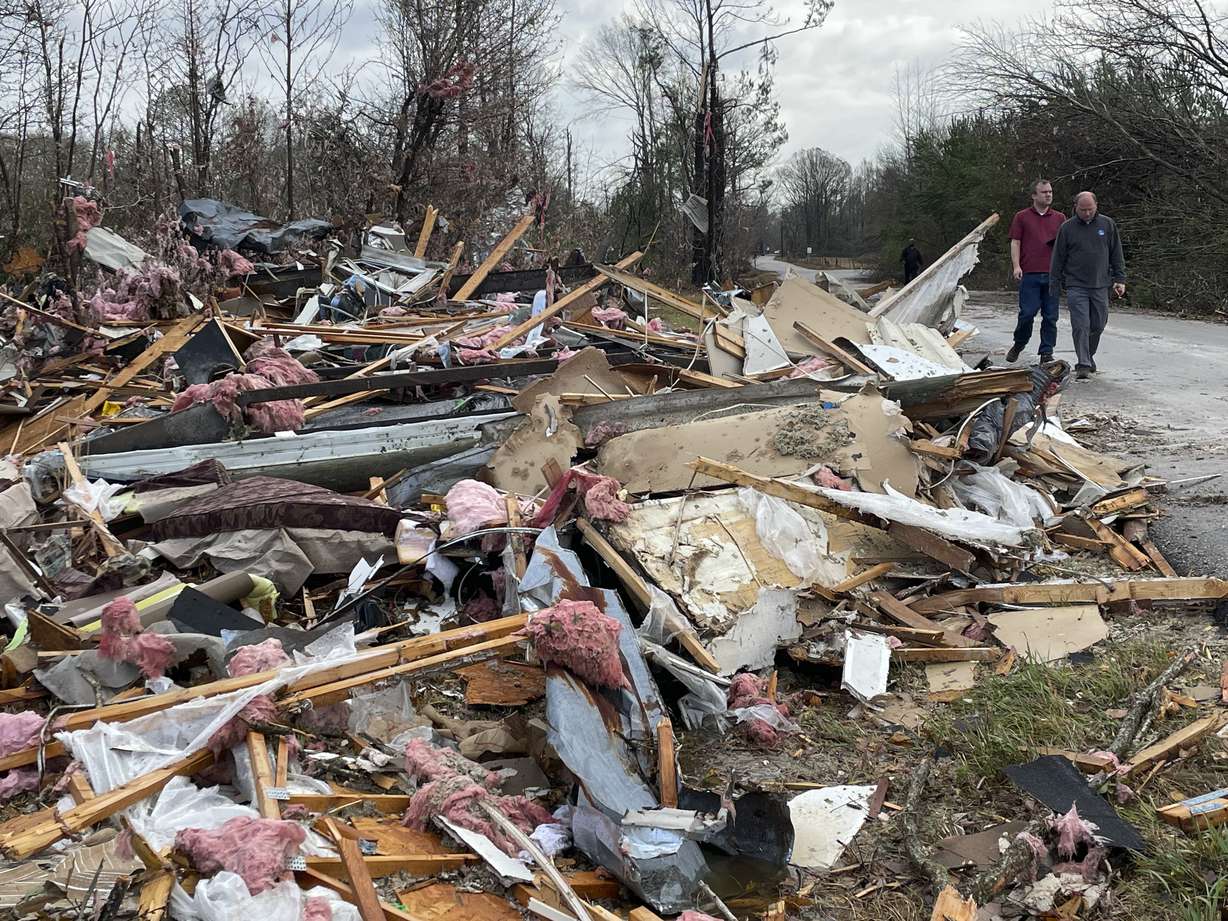 People walk through an area of destroyed structures in Flatwood, Ala. on Wednesday. Tornadoes damaged numerous homes, destroyed a fire station, briefly trapped people in a grocery store and ripped the roof off an apartment complex in Mississippi and Alabama.