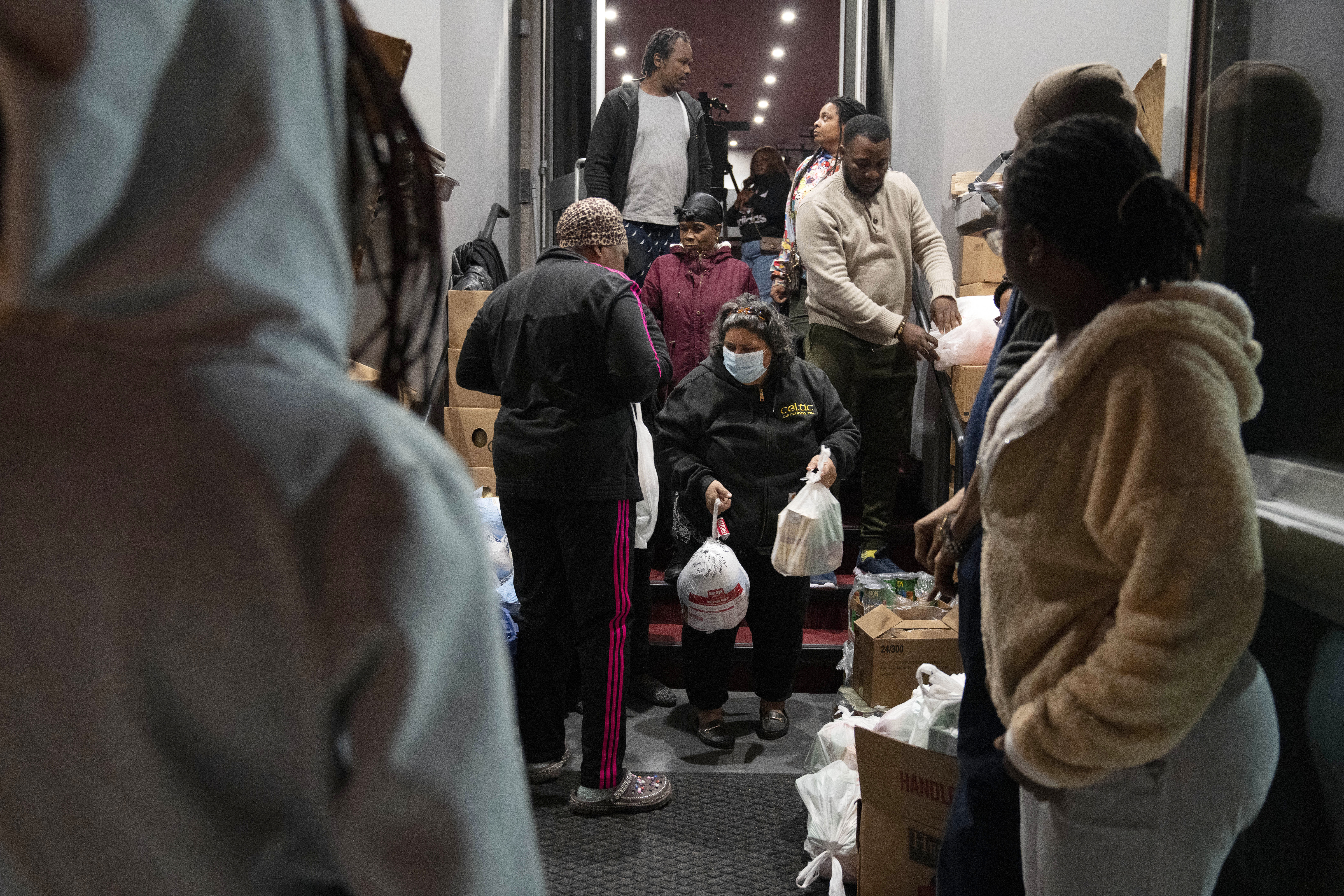 Maria Correa, of Washington, center, who says she is sick with cancer, cannot work, and that things are especially difficult because of the pandemic, accepts a turkey and Thanksgiving trimmings during an annual Thanksgiving food giveaway at The Redeemed Christian Church of God New Wine Assembly, Nov. 22, in Washington. 
