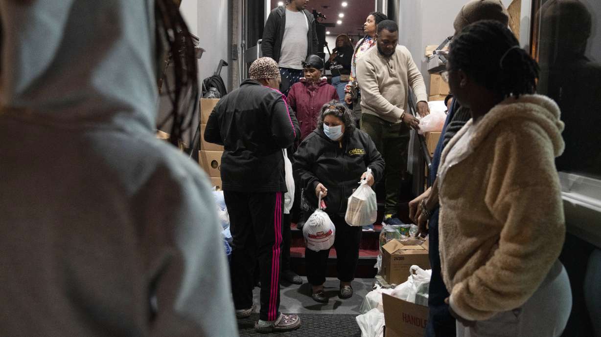 Maria Correa, of Washington, center, who says she is sick with cancer, cannot work, and that things are especially difficult because of the pandemic, accepts a turkey and Thanksgiving trimmings during an annual Thanksgiving food giveaway at The Redeemed Christian Church of God New Wine Assembly, Nov. 22, in Washington.