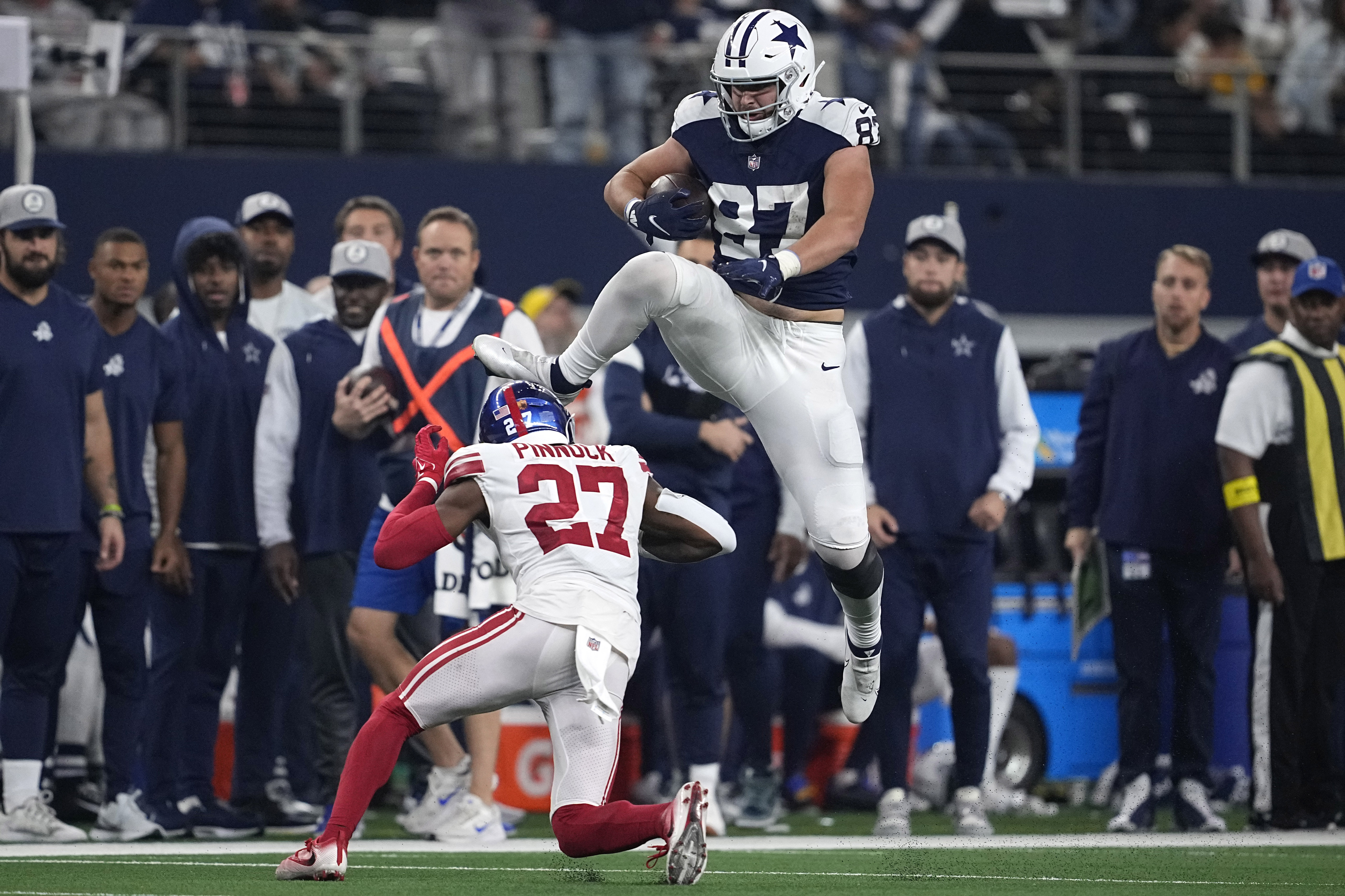 Dallas Cowboys tight end Jake Ferguson (87) leaps over New York Giants cornerback Jason Pinnock (27) during the second half of an NFL football game Thursday, Nov. 24, 2022, in Arlington, Texas.