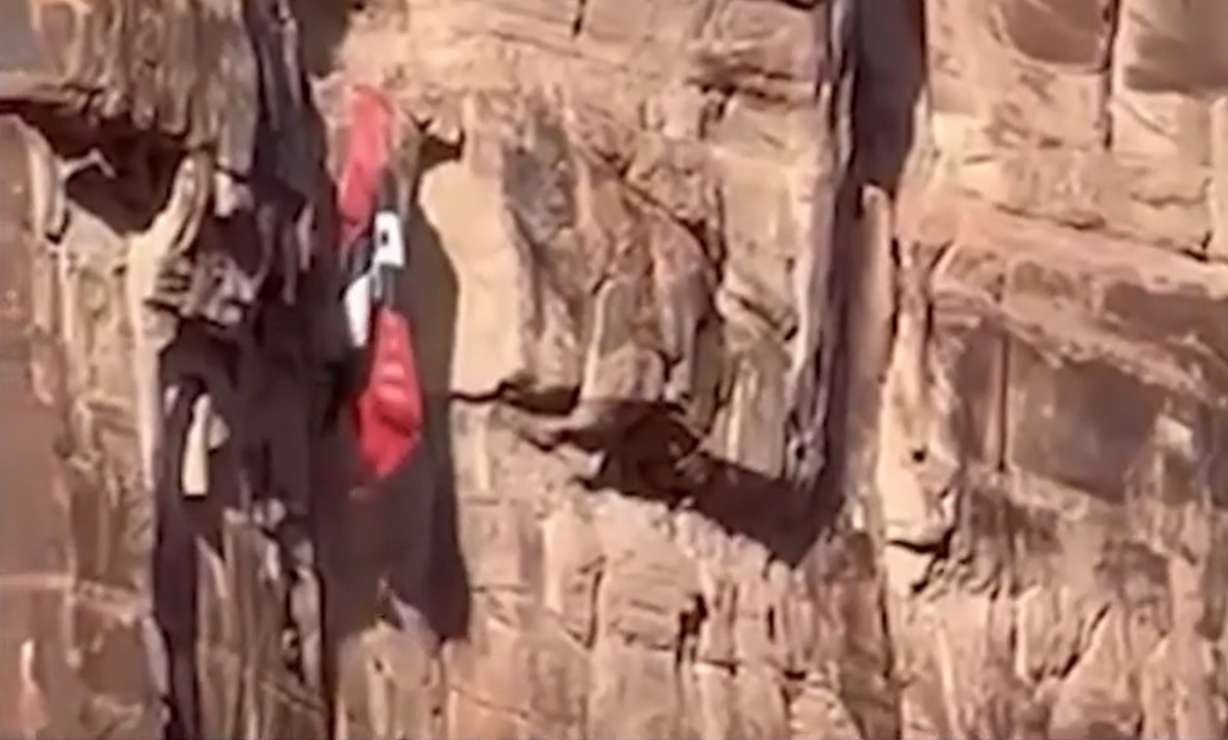 Incredible video shows the terrifying moments a BASE jumper crashed into a cliff in Moab on Saturday, then hung in the air high above the ground, his parachute stuck in the cliffside.