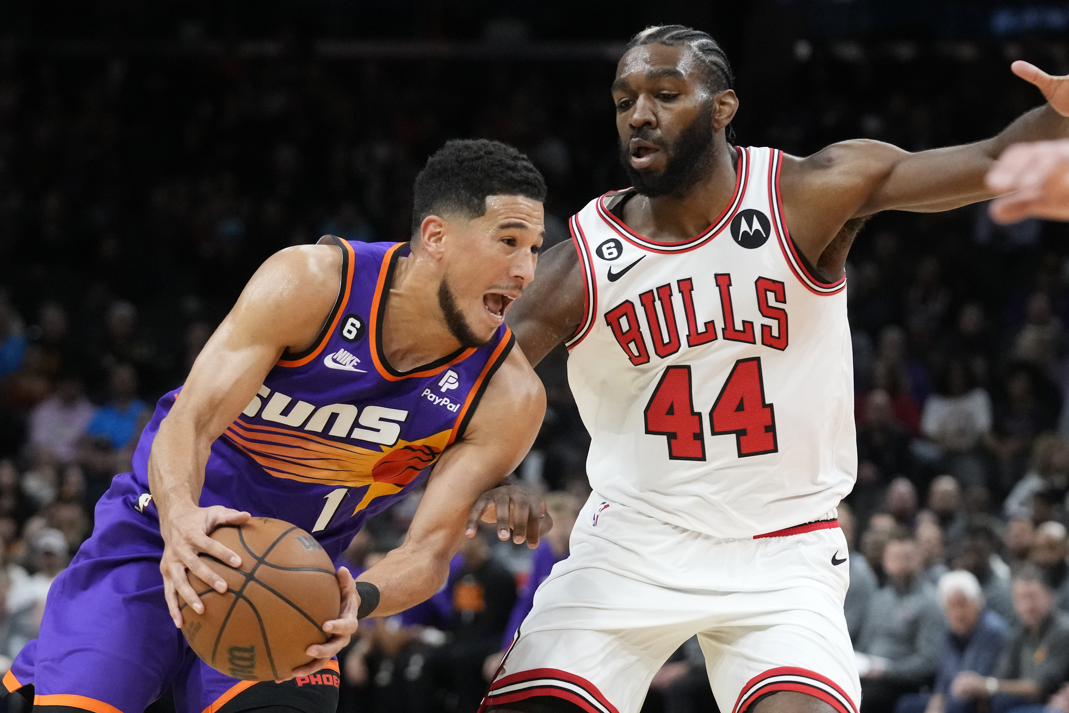 Phoenix Suns guard Devin Booker, left, drives past Chicago Bulls forward Patrick Williams (44) during the first half of an NBA basketball game in Phoenix, Wednesday, Nov. 30, 2022. 