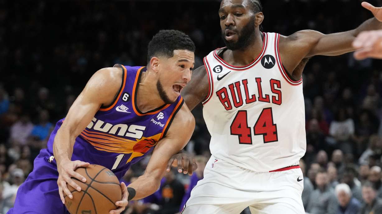 Phoenix Suns guard Devin Booker, left, drives past Chicago Bulls forward Patrick Williams (44) during the first half of an NBA basketball game in Phoenix, Wednesday, Nov. 30, 2022.