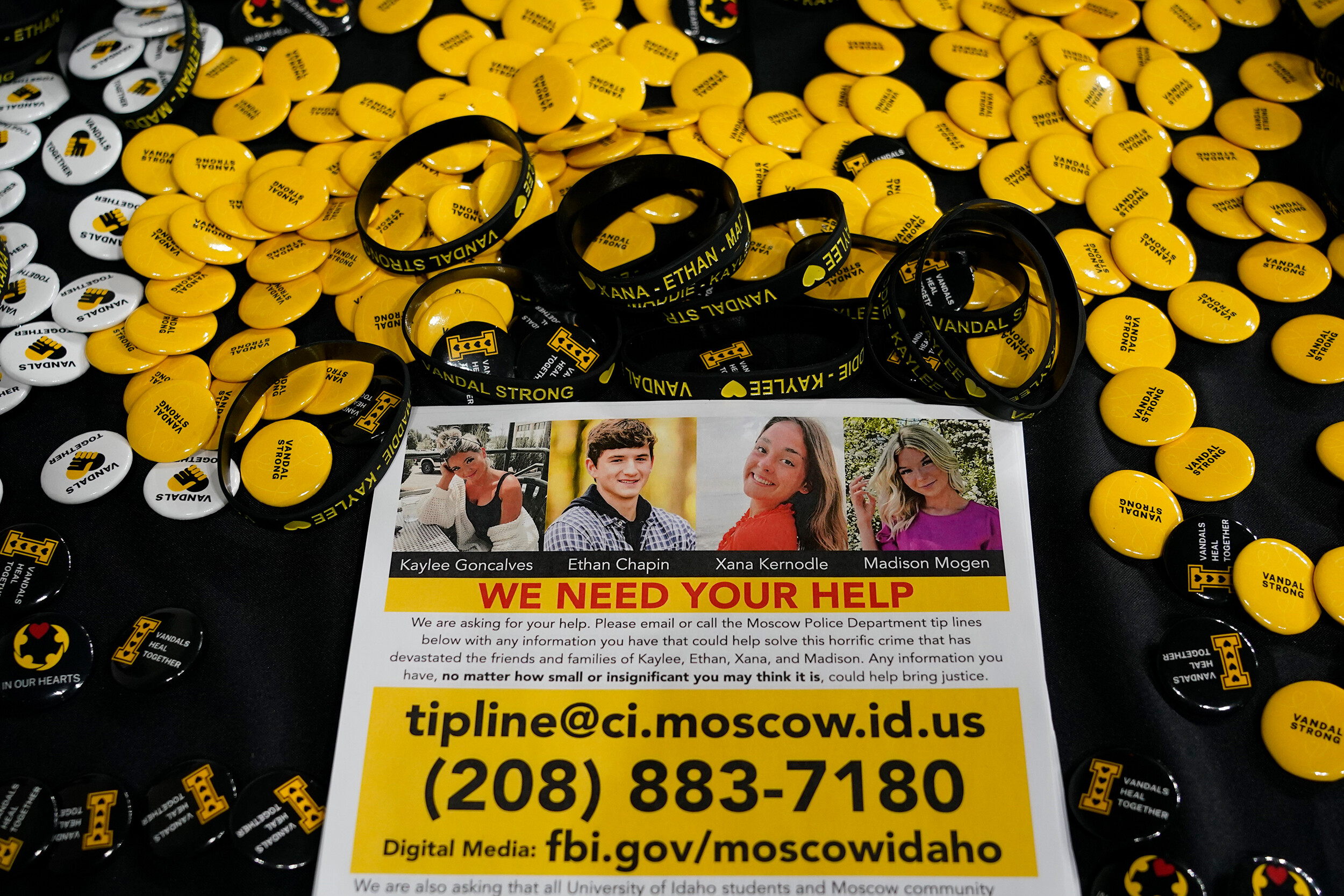 A flyer seeking information about the killings of four University of Idaho students is displayed on a table along with buttons and bracelets, Wednesday during a vigil in memory of the victims in Moscow, Idaho.