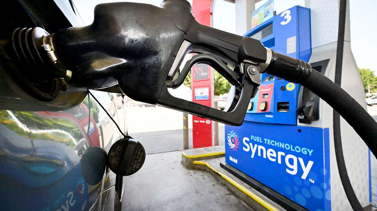 A gasoline nozzle pumps gas into a vehicle in Los Angeles on Aug. 23. Prices at the pump continue to plunge.