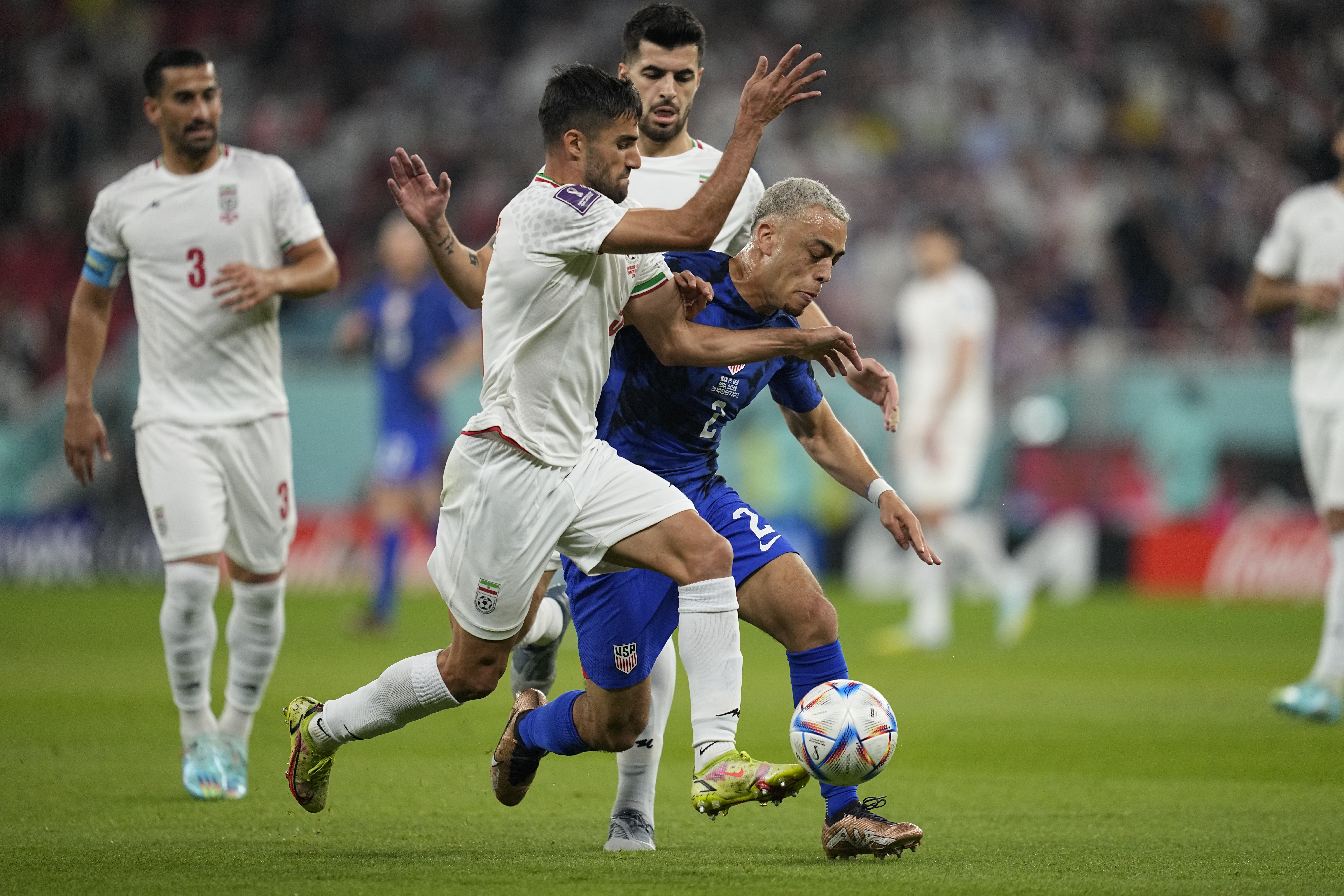 FILE - Sergino Dest of the United States fights for the ball with Iran's Milad Mohammadi during the World Cup group B soccer match between Iran and the United States at the Al Thumama Stadium in Doha, Qatar, Nov. 29, 2022. Iran's national soccer team received a subdued welcome home from Qatar late Wednesday, after its World Cup defeat against the United States, a match played against the backdrop of ongoing anti-government protests in Iran. One Iranian man was shot dead celebrating the American victory. 