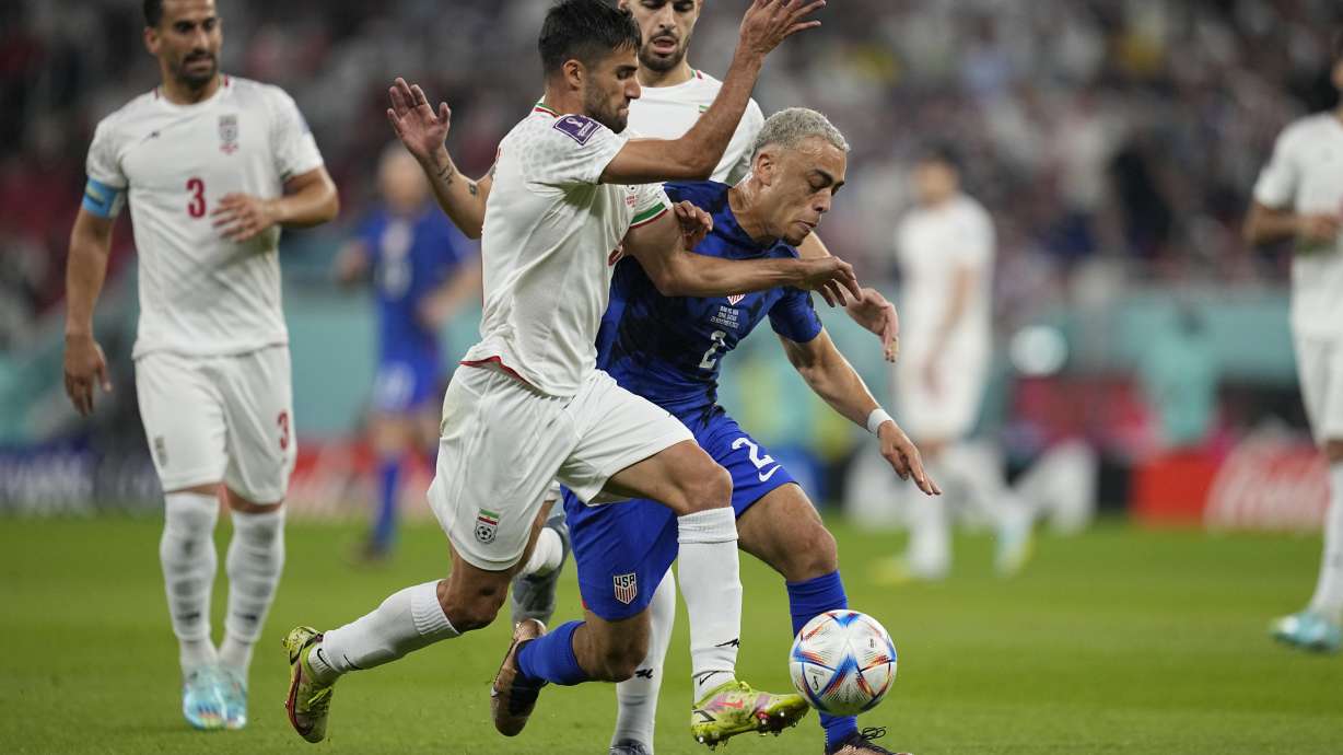 FILE - Sergino Dest of the United States fights for the ball with Iran's Milad Mohammadi during the World Cup group B soccer match between Iran and the United States at the Al Thumama Stadium in Doha, Qatar, Nov. 29, 2022. Iran's national soccer team received a subdued welcome home from Qatar late Wednesday, after its World Cup defeat against the United States, a match played against the backdrop of ongoing anti-government protests in Iran. One Iranian man was shot dead celebrating the American victory.