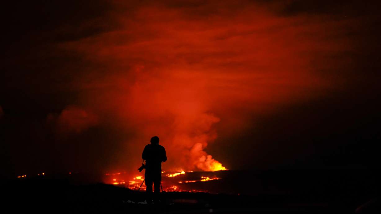 A photographer takes pictures of the Mauna Loa volcano as it erupts Wednesday, Nov. 30, near Hilo, Hawaii.