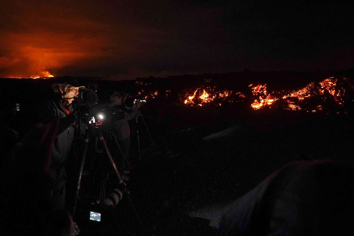 A journalist records images of lava from the Mauna Loa volcano as it erupts Wednesday, Nov. 30, near Hilo, Hawaii.