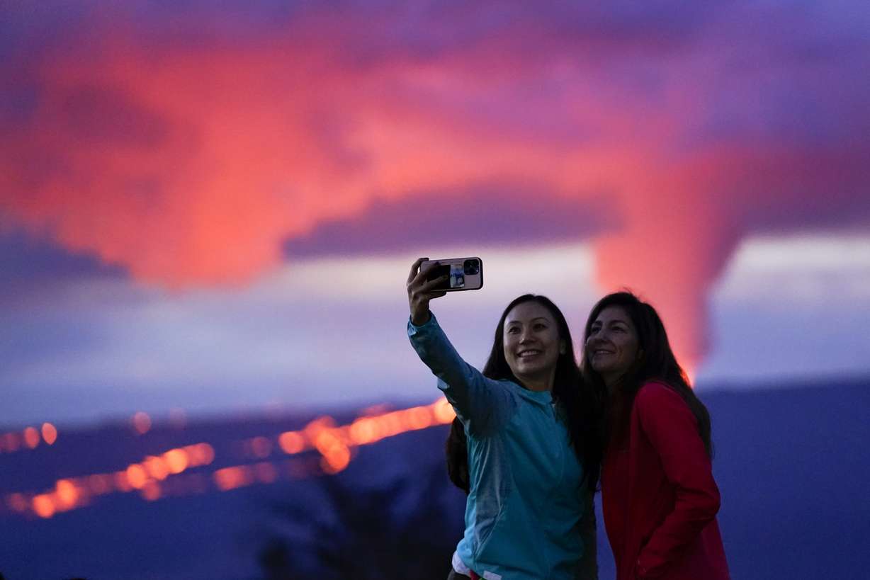 Ingrid Yang, left, and Kelly Bruno, both of San Diego, take a photo in front of lava erupting from Hawaii's Mauna Loa volcano Wednesday, Nov. 30, near Hilo, Hawaii.