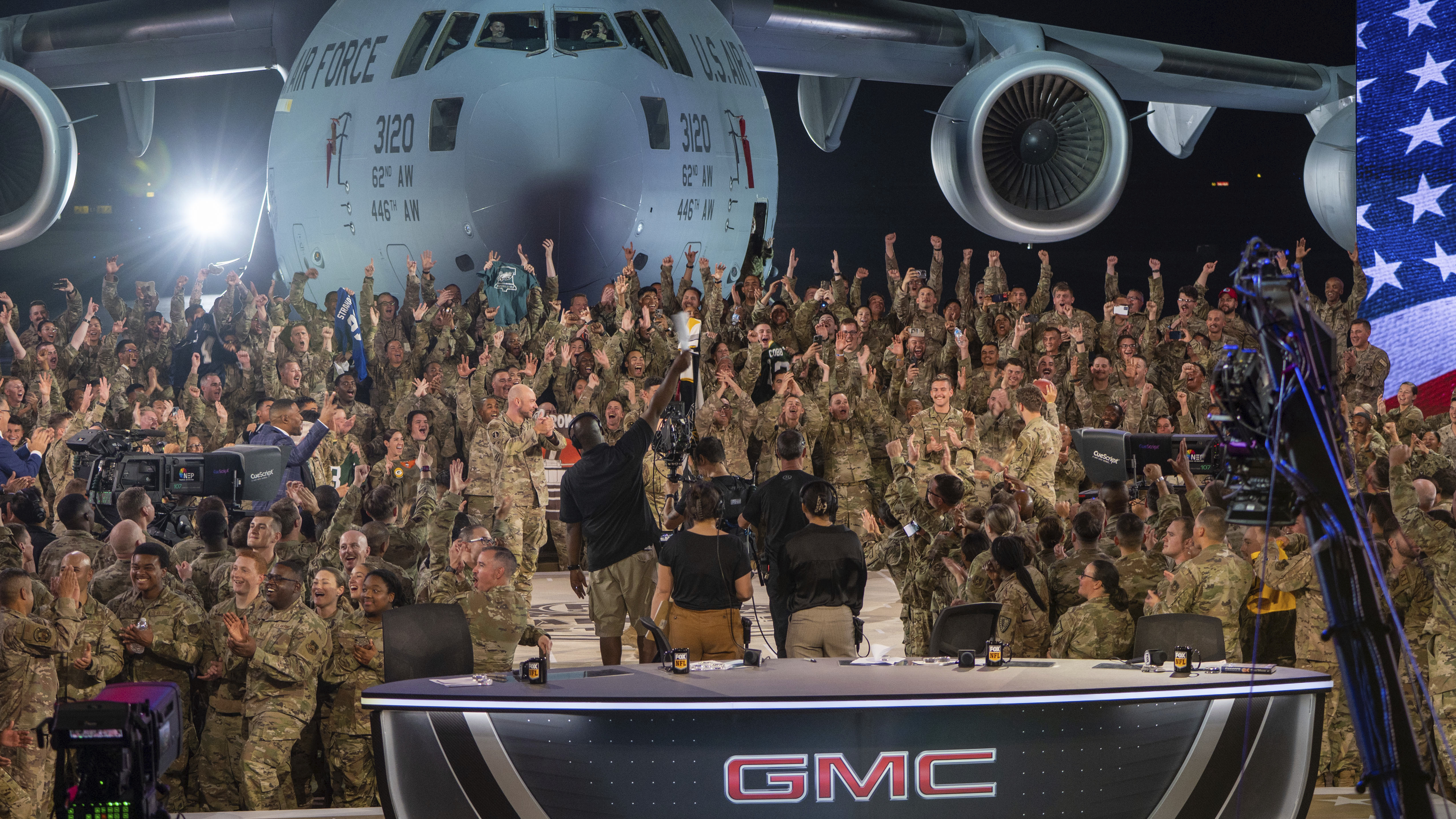 In this handout photo from the U.S. Air Force, American service members participate in a live broadcast with the hosts of Fox NFL Sunday during their Salute to Veterans broadcast, Nov. 13, 2022 at Al-Udeid Air Base in Qatar. As over a million World Cup fans fill stadiums with cheers and carry heady optimism through the streets of Doha, some 8,000 American troops are running air wars in Afghanistan, Iraq, Syria and other hotspots in the Middle East mere miles away. 