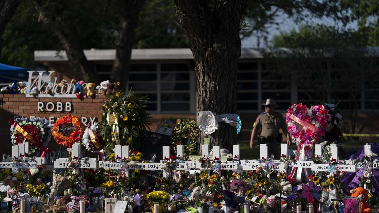 Flowers and candles are placed around crosses on May 28 at a memorial outside Robb Elementary School in Uvalde, Texas, to honor the victims killed in the school shooting a few days prior. Victims of the Uvalde school shooting that left 21 people dead have filed a lawsuit seeking $27 billion against local and state police, the city and other school and law enforcement officials, according to court documents.