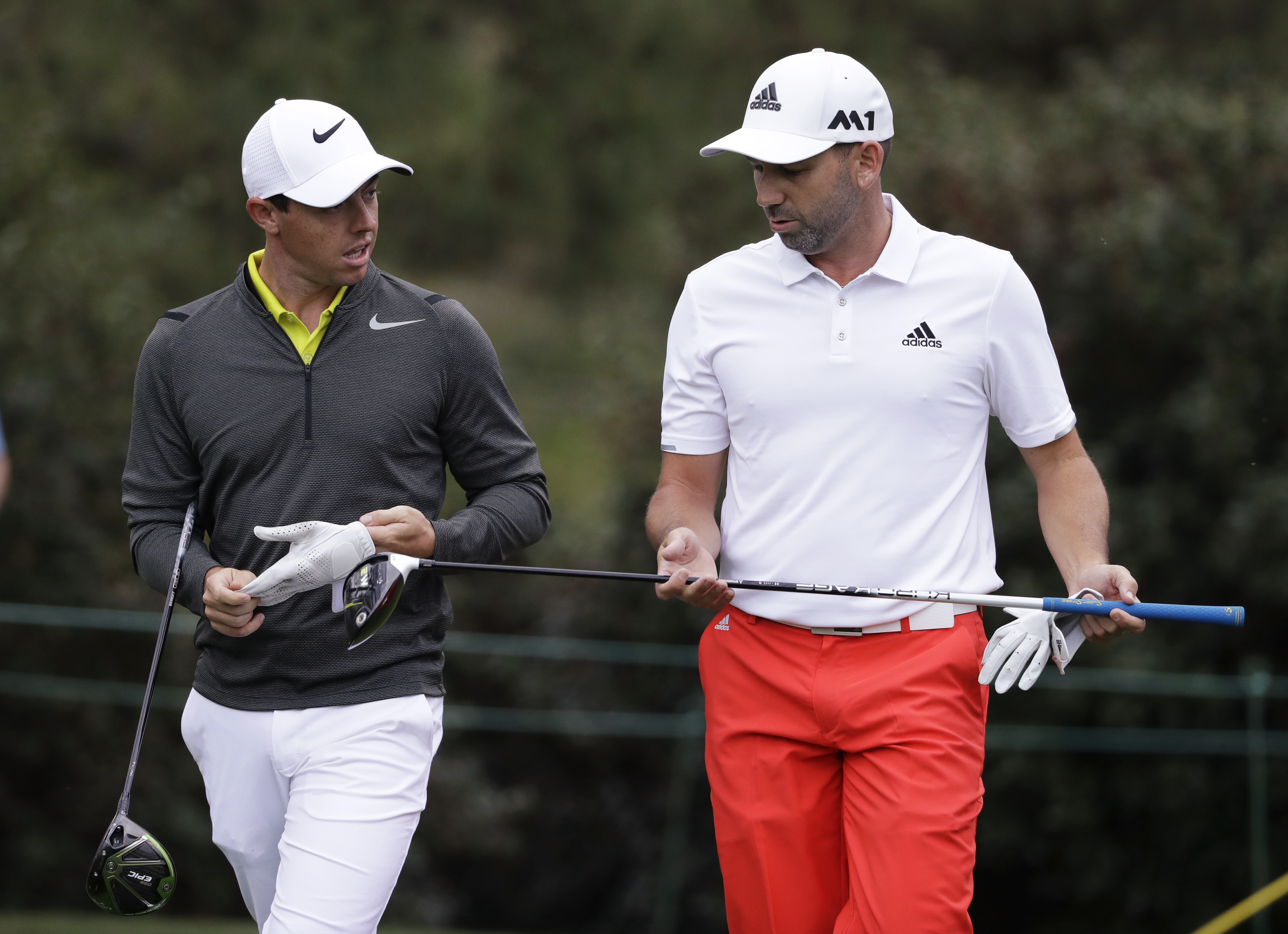 FILE - Rory McIlroy, left, of Northern Ireland, and Sergio Garcia, of Spain, walk up the 15th fairway during a practice round for the Masters golf tournament April 5, 2017, in Augusta, Ga. McIlroy, in a lengthy interview in the Sunday Independent in Ireland, says his close friendship with Garcia ended over a testy text exchange at the U.S. Open. 