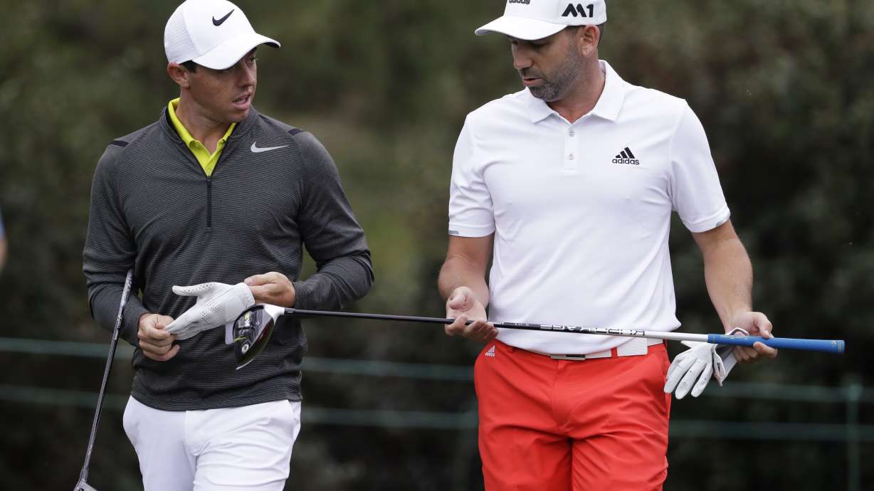 FILE - Rory McIlroy, left, of Northern Ireland, and Sergio Garcia, of Spain, walk up the 15th fairway during a practice round for the Masters golf tournament April 5, 2017, in Augusta, Ga. McIlroy, in a lengthy interview in the Sunday Independent in Ireland, says his close friendship with Garcia ended over a testy text exchange at the U.S. Open.