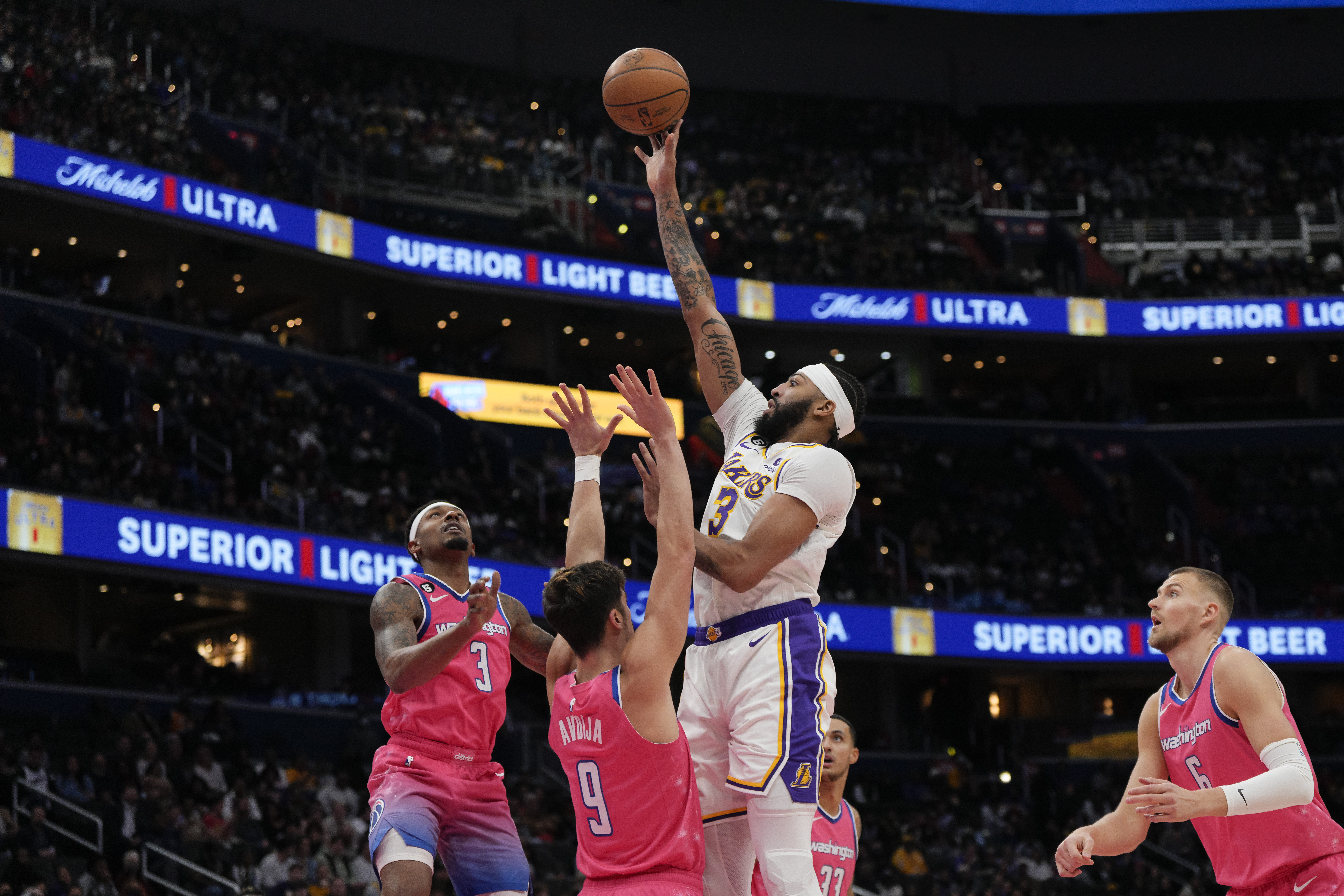 Los Angeles Lakers forward Anthony Davis, center, scores as Washington Wizards guard Bradley Beal, left, and forward Deni Avdija (9) defend during the first half of an NBA basketball game, Sunday, Dec. 4, 2022, in Washington. 