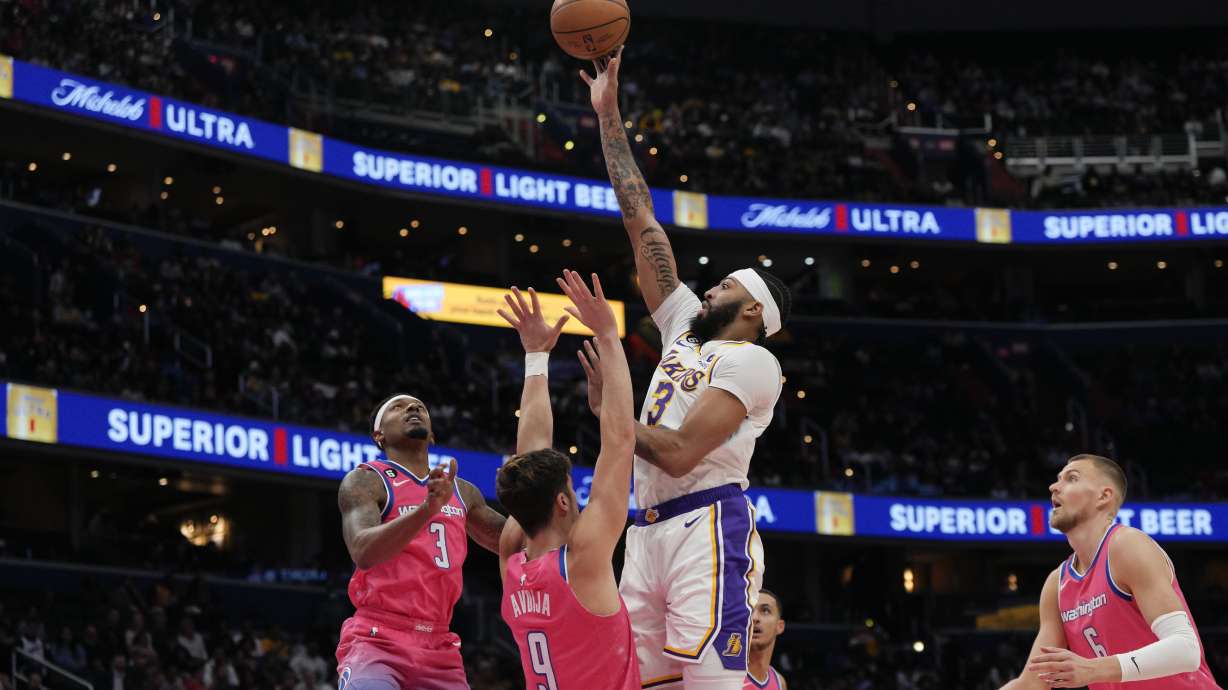 Los Angeles Lakers forward Anthony Davis, center, scores as Washington Wizards guard Bradley Beal, left, and forward Deni Avdija (9) defend during the first half of an NBA basketball game, Sunday, Dec. 4, 2022, in Washington.