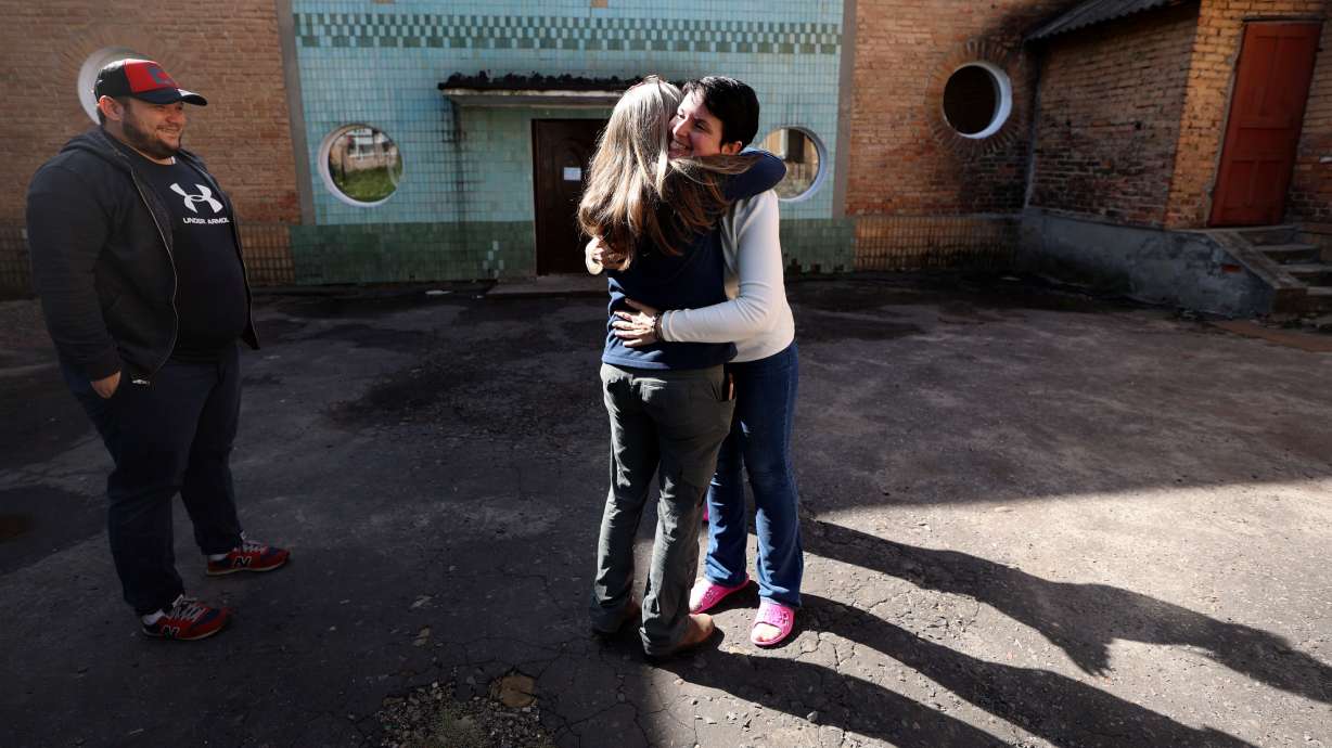 Yurii Slepak, WelcomeNST country director for Ukraine, watches as Liz Davis-Edwards, WelcomeNST CEO, hugs Elvira Karnaukh outside of Chervonohrad Kindergarten No. 12, in Chervonohrad, Ukraine, on Sept. 17. On Sept. 20, Karnaukh left Ukraine with her two children, starting their journey with WelcomeNST to Lehi, Utah.