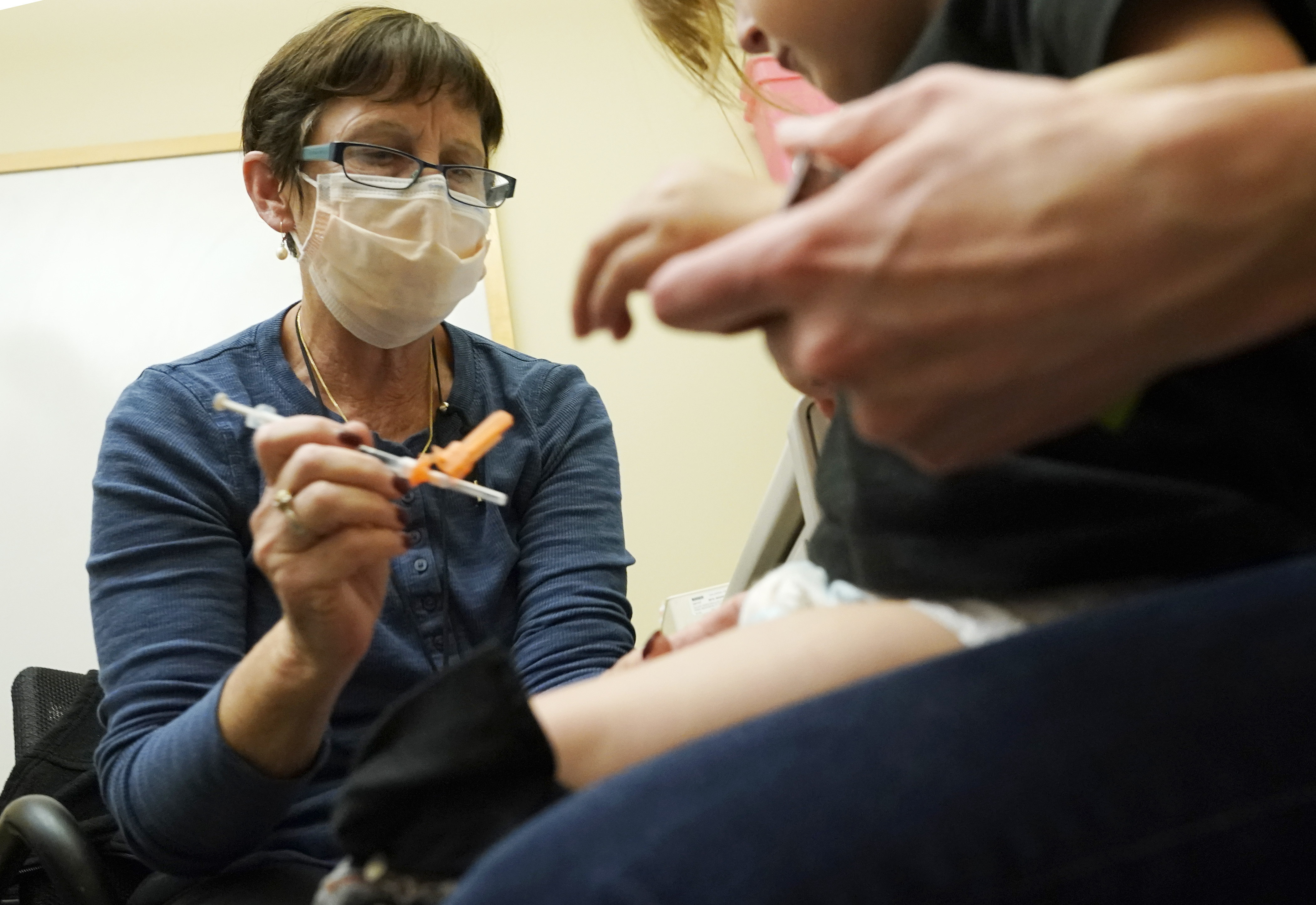 Deborah Sampson, left, a nurse at a University of Washington Medical Center clinic in Seattle, gives a Pfizer COVID-19 vaccine shot to a 20-month-old child, June 21, in Seattle. Pfizer is asking U.S. regulators to authorize its updated COVID-19 vaccine for children under age 5.