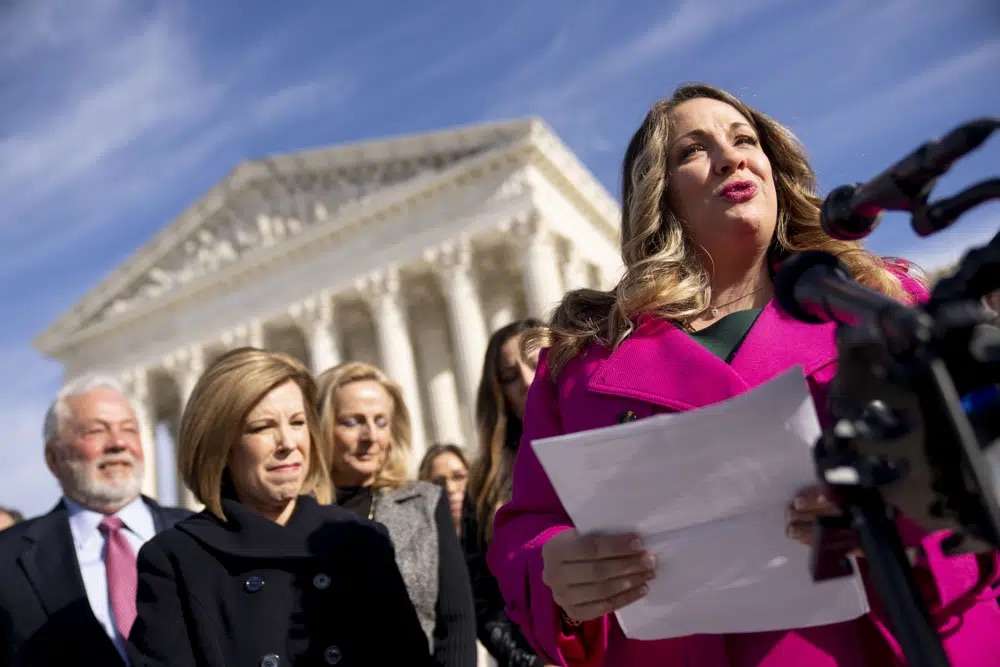 Lorie Smith, a Christian graphic artist and website designer in Colorado, right, accompanied by her lawyer, Kristen Waggoner of the Alliance Defending Freedom, second from left, speaks outside the Supreme Court in Washington, Monday, after her case was heard before the Supreme Court.