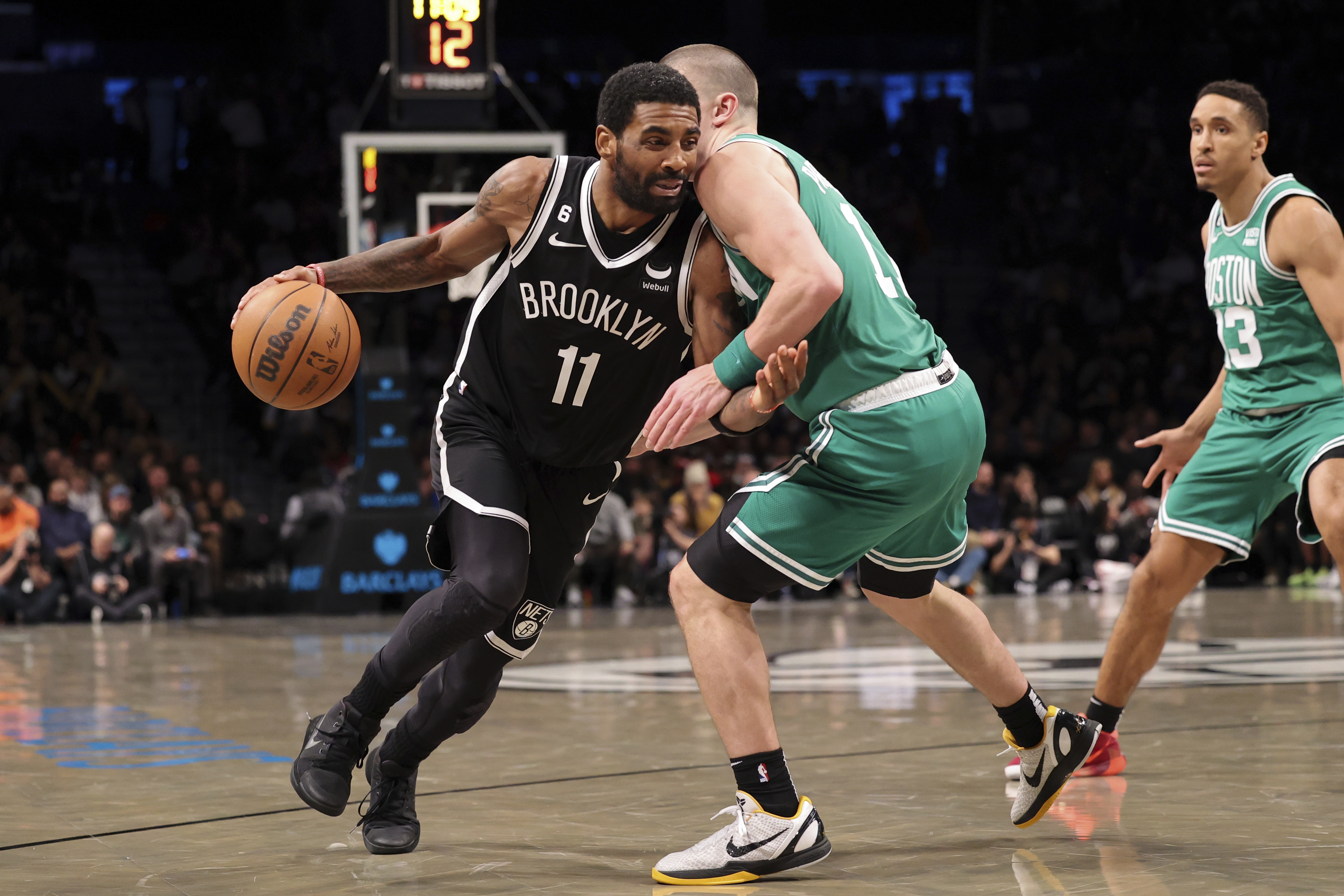 Brooklyn Nets guard Kyrie Irving (11) dribbles against Boston Celtics guard Payton Pritchard (11) as Boston Celtics guard Malcolm Brogdon (13) watches during the second half of an NBA basketball game, Sunday, Dec. 4, 2022, in New York. 