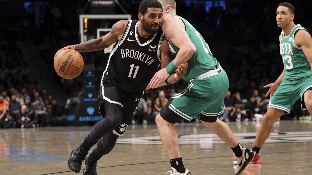 Brooklyn Nets guard Kyrie Irving (11) dribbles against Boston Celtics guard Payton Pritchard (11) as Boston Celtics guard Malcolm Brogdon (13) watches during the second half of an NBA basketball game, Sunday, Dec. 4, 2022, in New York.