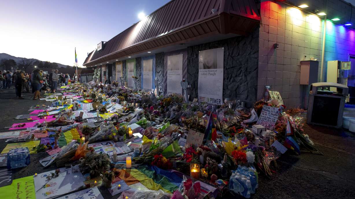 Mourners gather outside Club Q to visit a memorial on Nov. 25 in Colorado Spring, Colo. The suspect accused of shooting and killing five people and wounding 17 at the gay nightclub was formally charged with 305 criminal charges, including hate crimes and murder Tuesday.