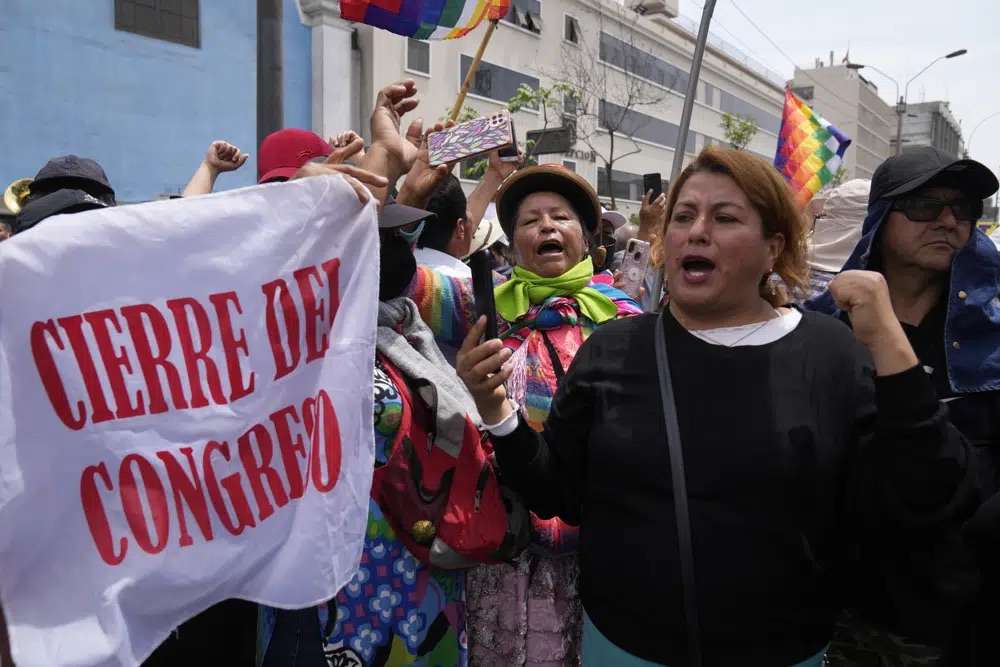 Supporters of Peruvian President Pedro Castillo rally with a flag that reads in Spanish "Closure of Congress" on the day of a planned impeachment vote on the president, near Congress in Lima, Peru, Wednesday. Castillo dissolved the nation's Congress on Wednesday and called for new legislative elections before lawmakers could debate a third attempt to remove him from office.
