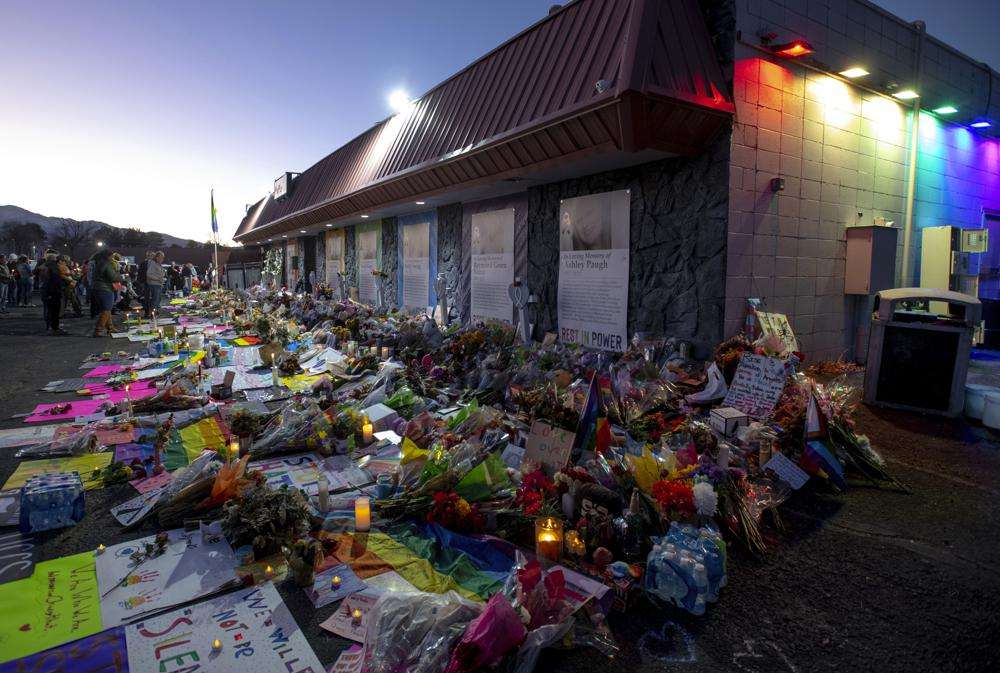 Mourners gather outside Club Q to visit a memorial, which has been moved from a sidewalk outside of police tape that was surrounding the club, on Friday in Colorado Spring, Colo. The suspect accused of entering the gay nightclub clad in body armor and opening fire with an AR-15-style rifle, killing five people and wounding 17 others, is set to appear in court again Tuesday, Dec. 6 to learn what charges prosecutors will pursue in the attack, including possible hate crime counts.