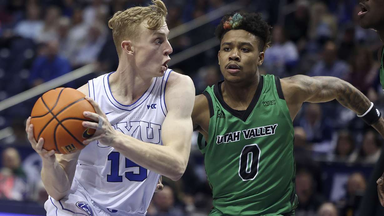 Brigham Young guard Richie Saunders (15) drives past Utah Valley guard Justin Harmon (0) at BYU in Provo on Wednesday, Dec. 7, 2022.