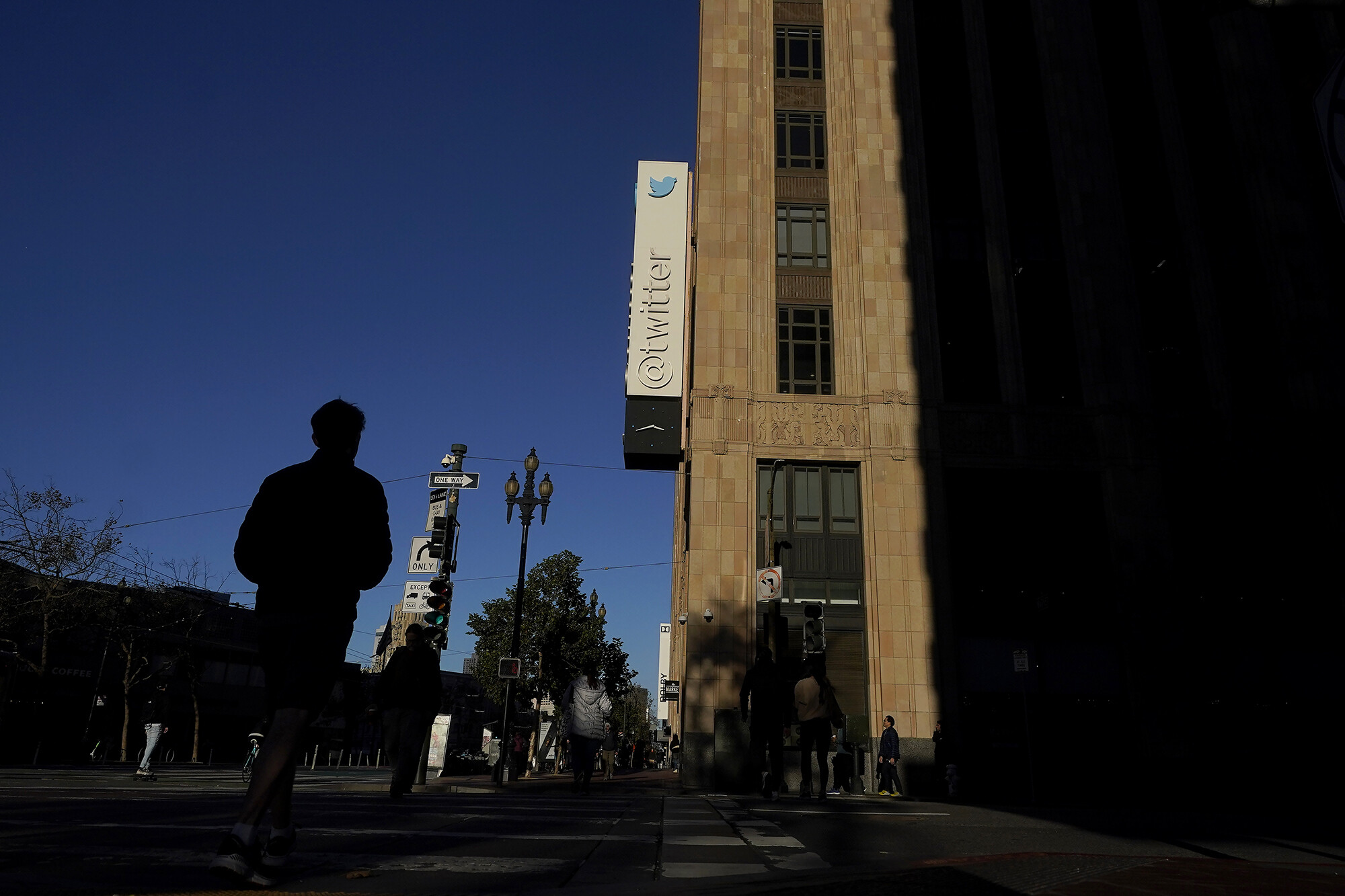 People walk outside of Twitter headquarters in San Francisco on Nov. 18. A group of former Twitter employees who are suing the company spoke out on Thursday, alleging that new owner Elon Musk's mass layoffs at the company have triggered multiple labor rights violations.