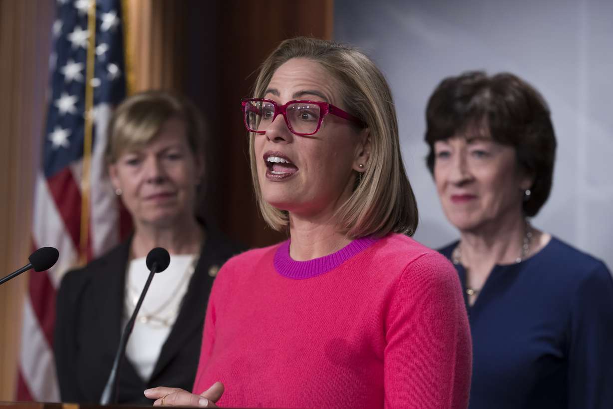 Sen. Kyrsten Sinema, D-Ariz., flanked by Sen. Tammy Baldwin, D-Wis., left, and Sen. Susan Collins, R-Maine, speaks to reporters following Senate passage of the Respect for Marriage Act, at the Capitol in Washington, Nov. 29.