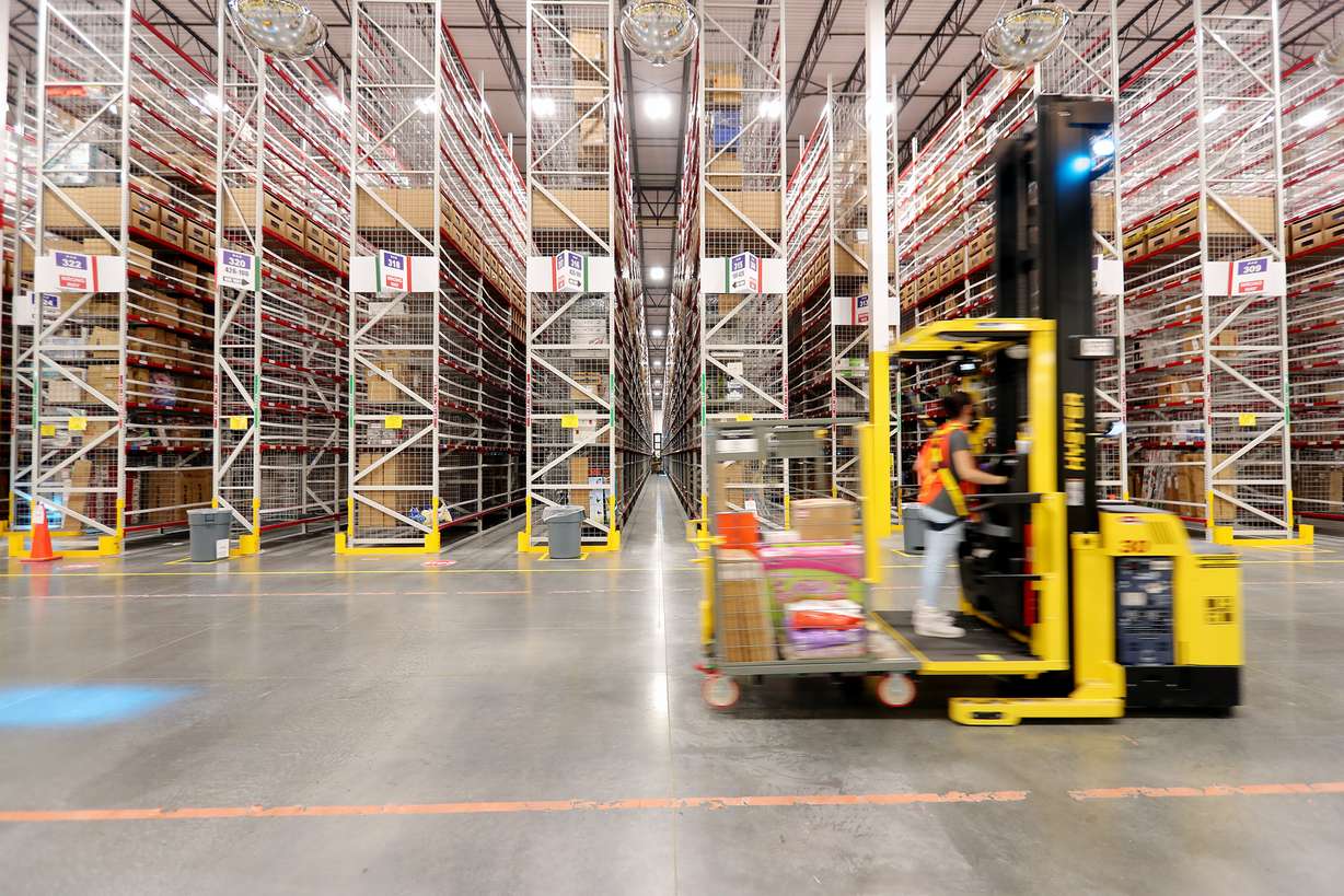 A worker operates a lift as it moves from isle to isle retrieving products inside the newly opened Amazon fulfillment center in West Jordan on Sept. 14, 2020.