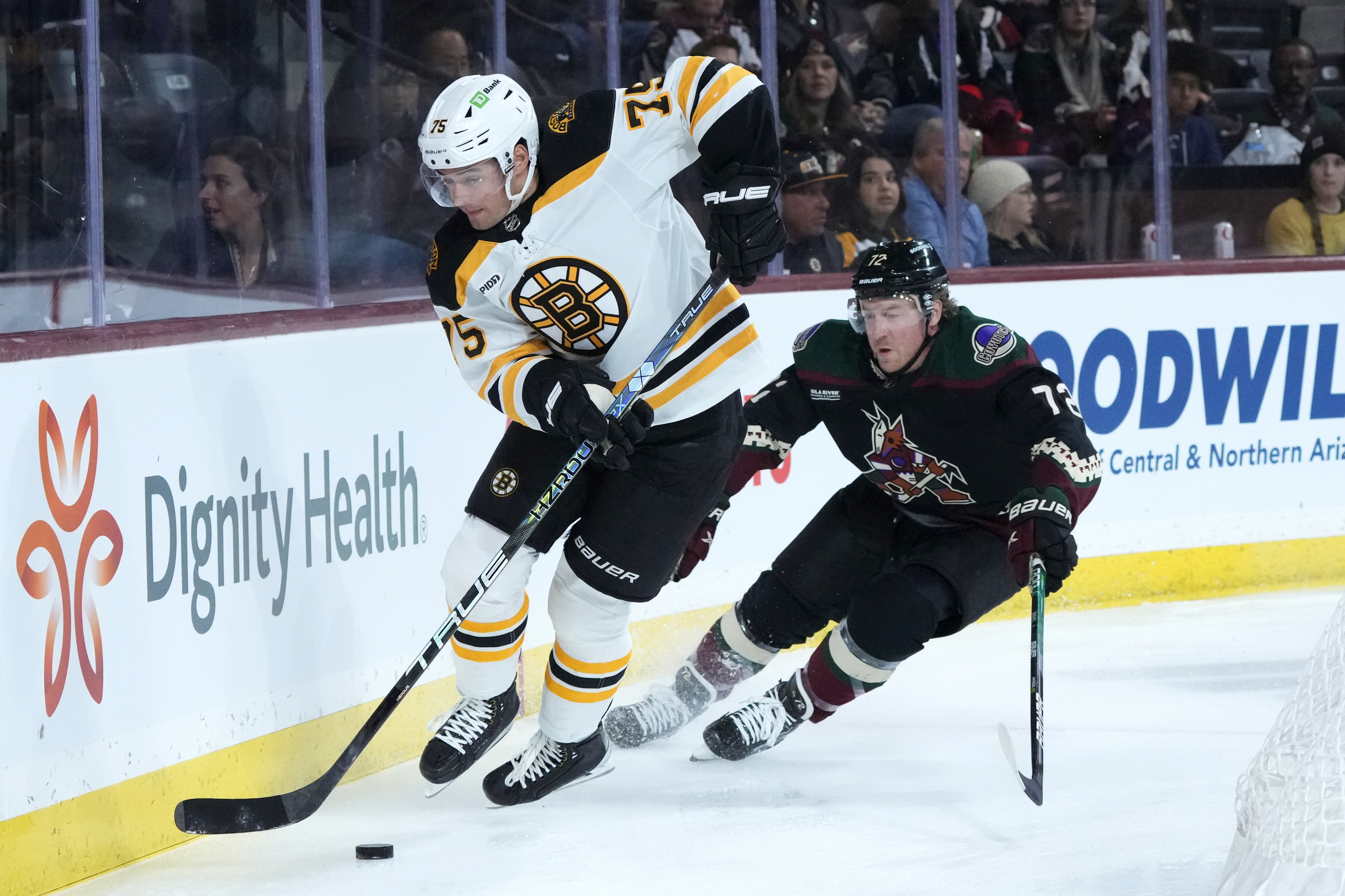 Boston Bruins defenseman Connor Clifton (75) skates with the puck against Arizona Coyotes center Travis Boyd (72) during the first period of an NHL hockey game in Tempe, Ariz., Friday, Dec. 9, 2022. 