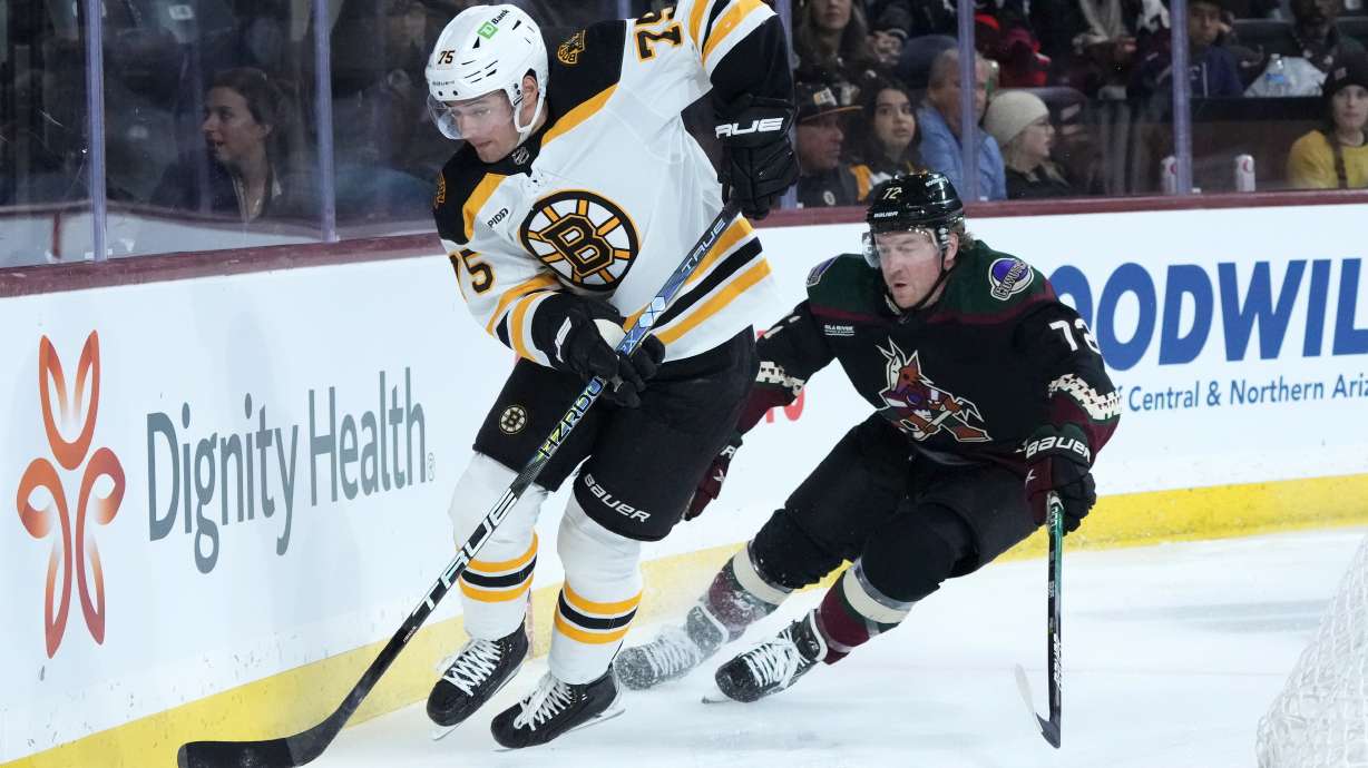 Boston Bruins defenseman Connor Clifton (75) skates with the puck against Arizona Coyotes center Travis Boyd (72) during the first period of an NHL hockey game in Tempe, Ariz., Friday, Dec. 9, 2022.