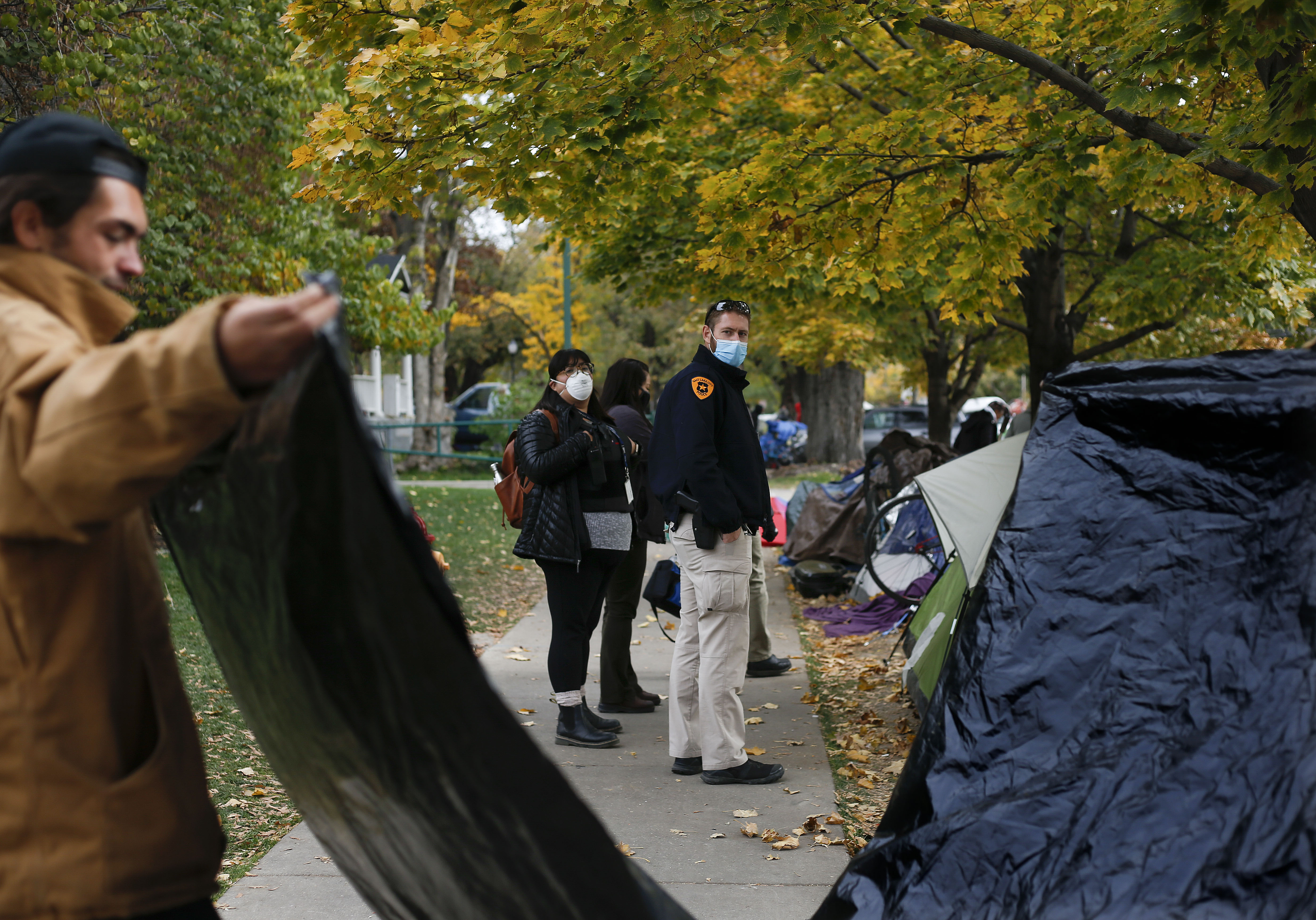 Salt Lake detective Joseph Taylor and social worker Karen Montano watch as homeless people pack up their belongings prior to being evicted from Taufer Park in Salt Lake City Oct. 23, 2020.