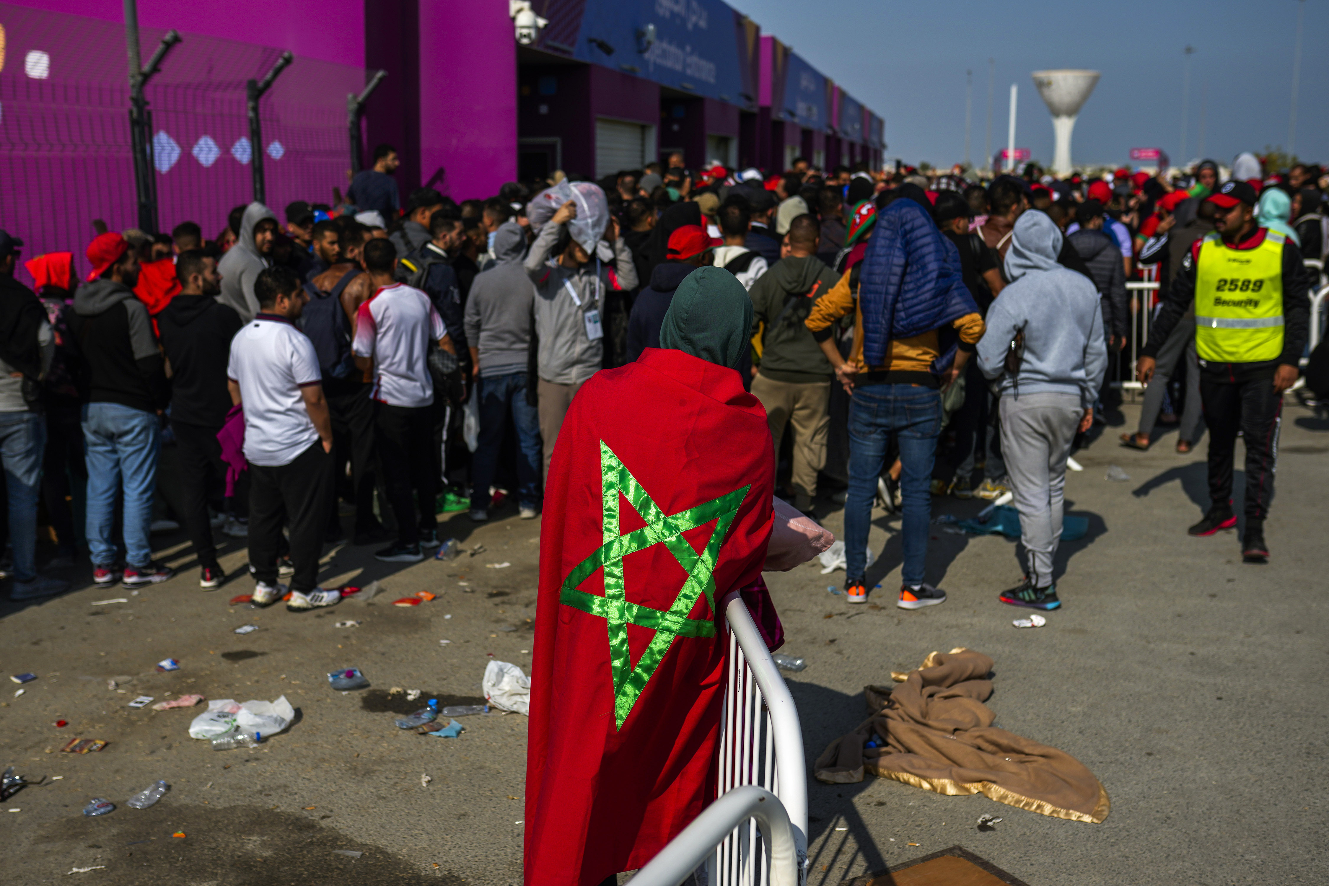 A man draped in a Moroccan flag queues with supporters outside the Al Janoub Stadium in Wakrah, Qatar on Tuesday, Dec. 13, 2022 in the hope of getting tickets for Wednesday's World Cup semifinal soccer match between France and Morocco. 