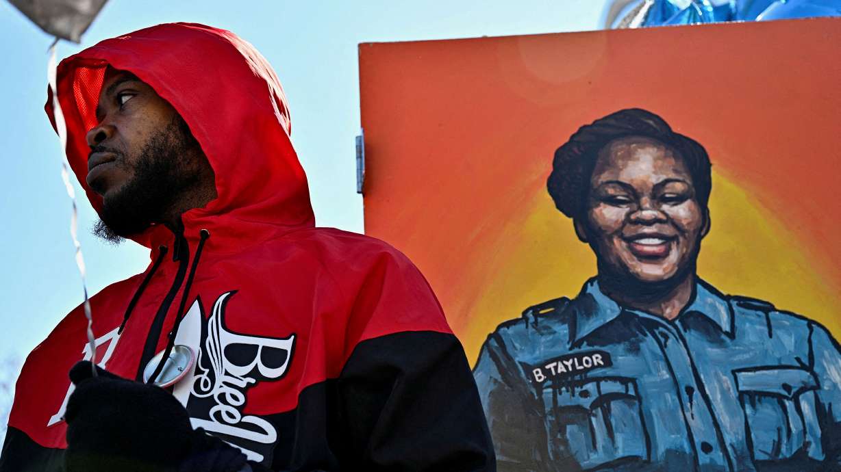 Breonna Taylor's boyfriend, Kenneth Walker III, has reached a $2 million dollar settlement with the City of Louisville. Walker (left) stands next to a painting of Breonna Taylor at a gathering in March, on the second anniversary of her death.