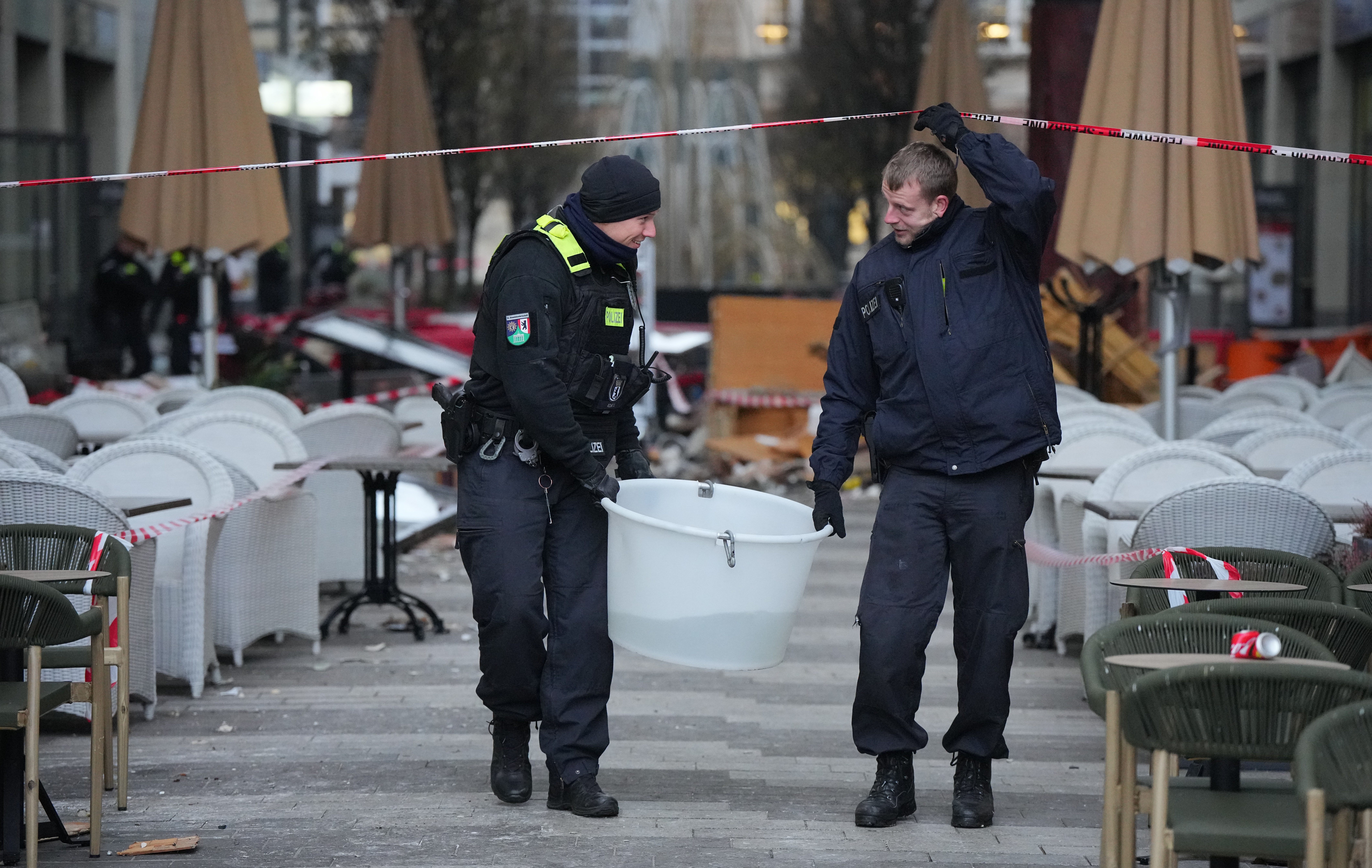 Police officers carry a plastic tub with rescued fish after a huge aquarium bursts in Berlin, Germany, Friday. German police say a huge fish tank in the center of Berlin has burst, causing a wave of devastation in and around the Sea Life tourist attraction. 