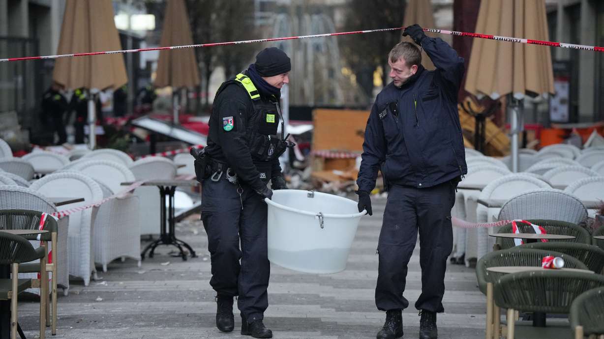 Police officers carry a plastic tub with rescued fish after a huge aquarium bursts in Berlin, Germany, Friday. German police say a huge fish tank in the center of Berlin has burst, causing a wave of devastation in and around the Sea Life tourist attraction.