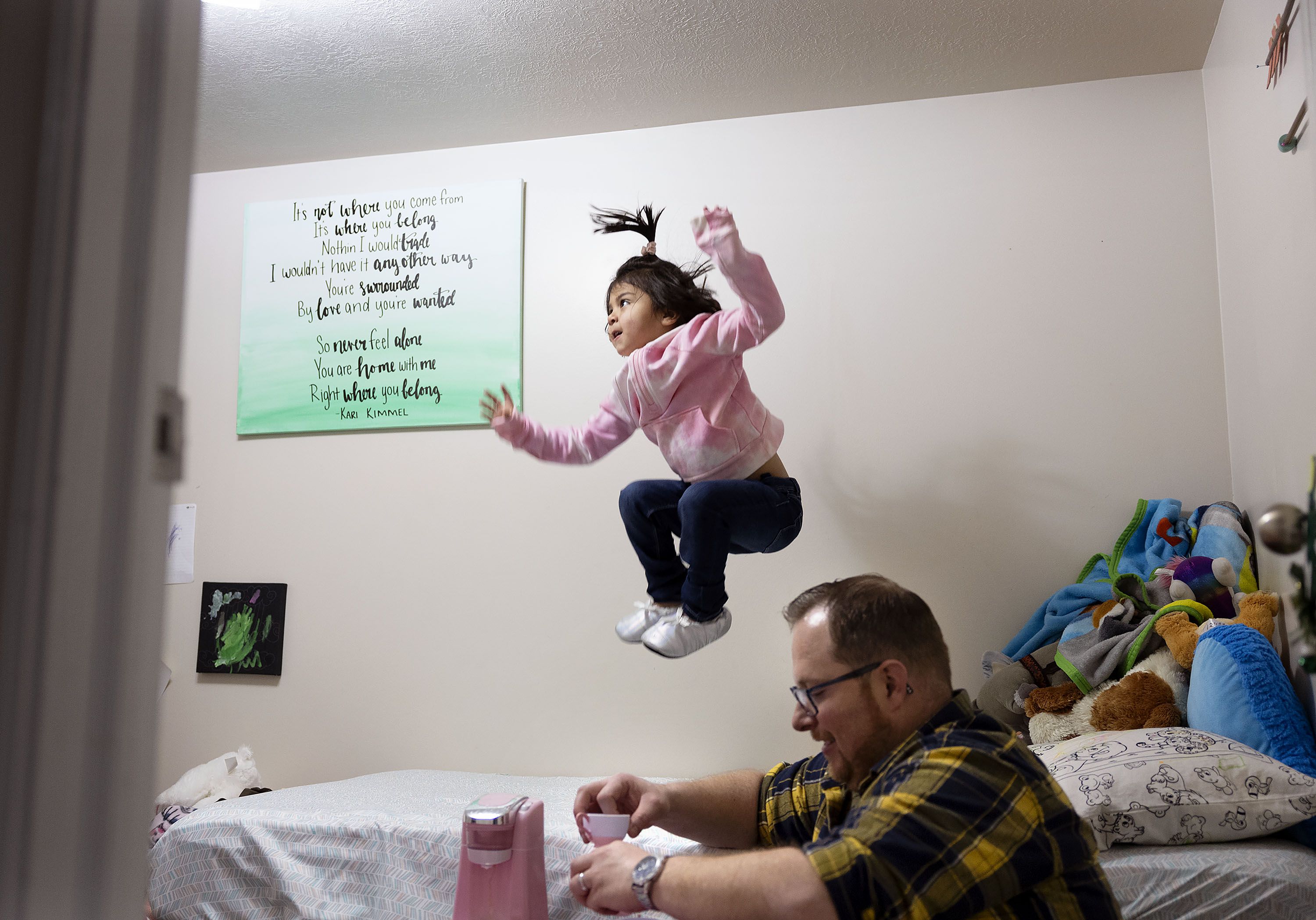 Matthew McKnight cleans up after a tea party with his daughter Madison while she jumps on her bed at their Sandy home on Friday. Matthew and his wife, Amanda, fostered Madison from the time she was born until her adoption was finalized.