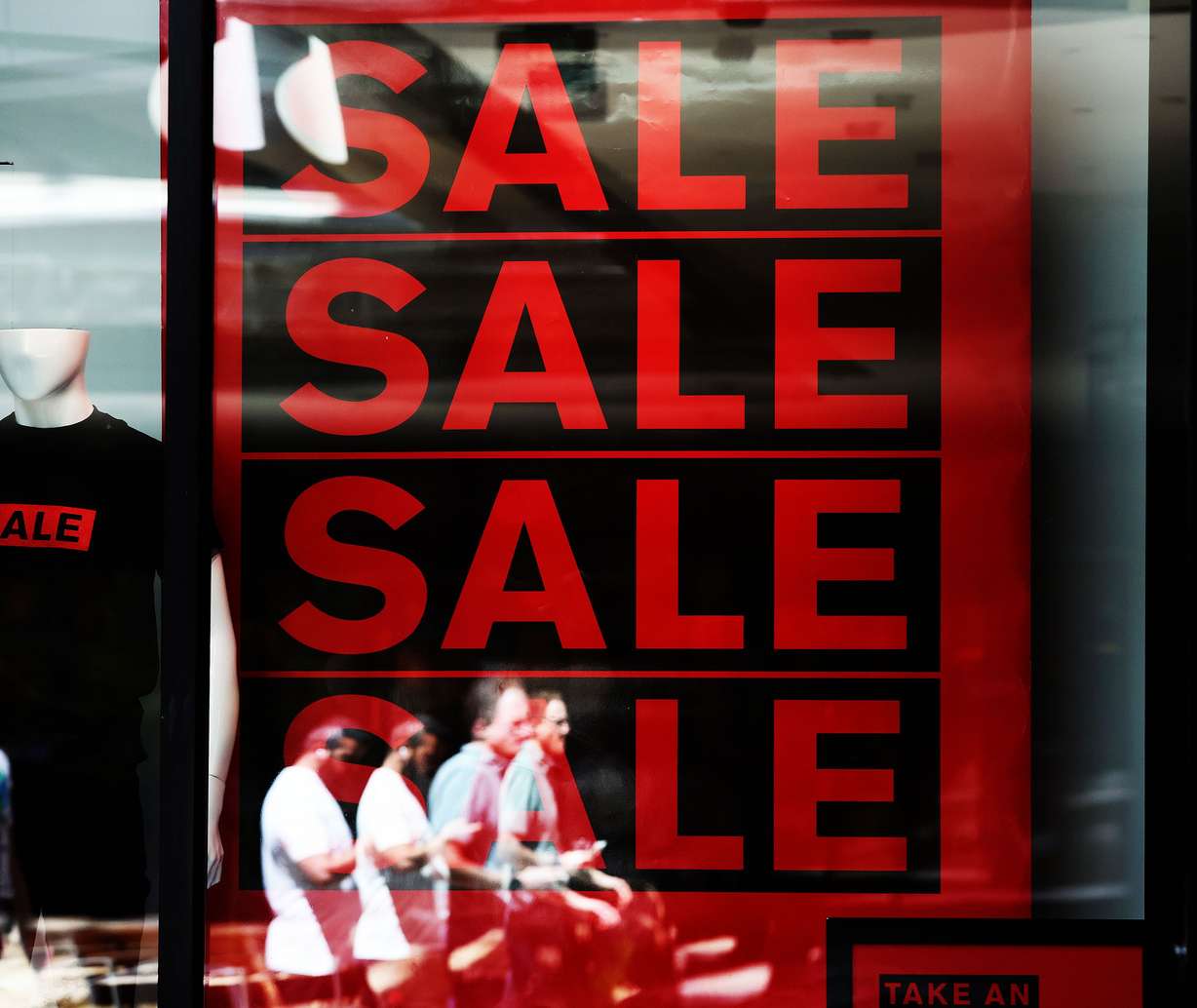 Shoppers walk by a sale sign at Express Men in City Creek Center in Salt Lake City on Aug. 17. A Census Bureau report shows U.S. consumer spending continues to run at record volume in spite of persistent, record-high inflation.