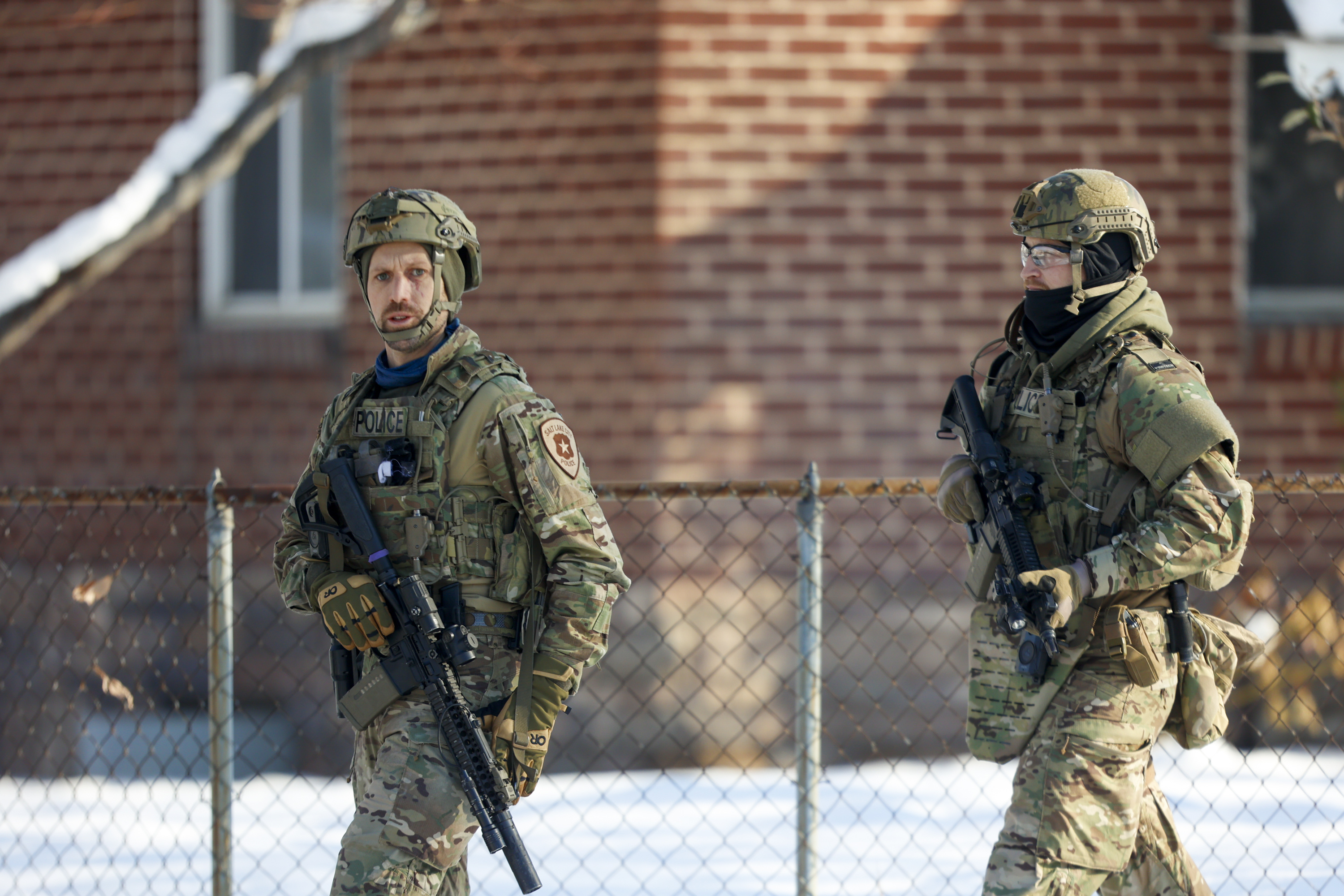 Officers walks down a street during a manhunt in Salt Lake City on Sunday. The man they were looking for allegedly forced residents of a Salt Lake neighborhood to seek shelter in their homes after fired off multiple rounds before entering an elderly woman's home.